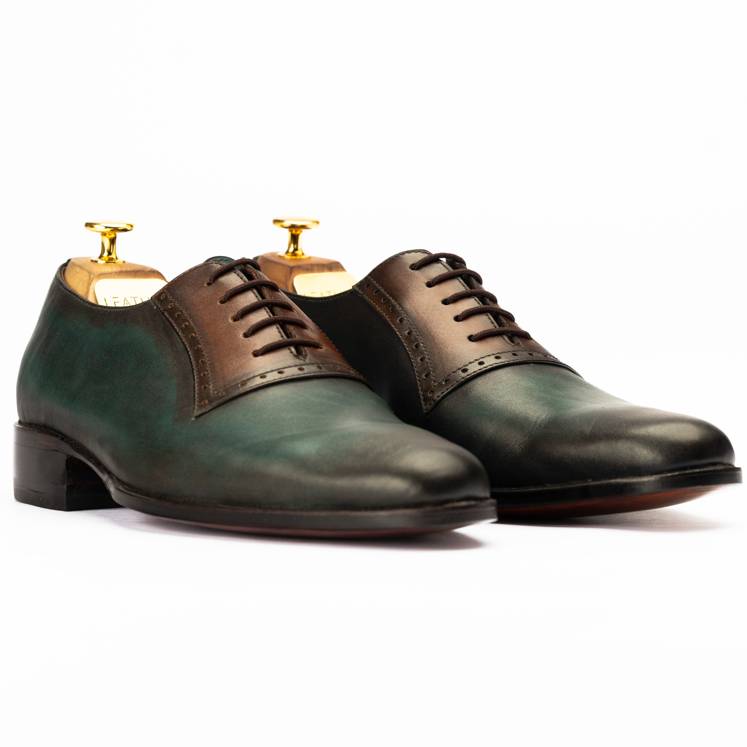 Pair of green and brown leather dress shoes on a white background