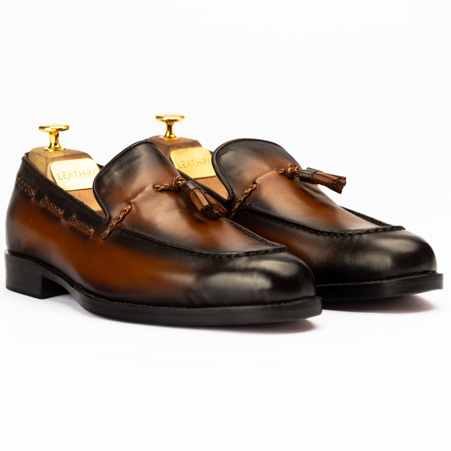Pair of brown leather loafers with tassels on a white background