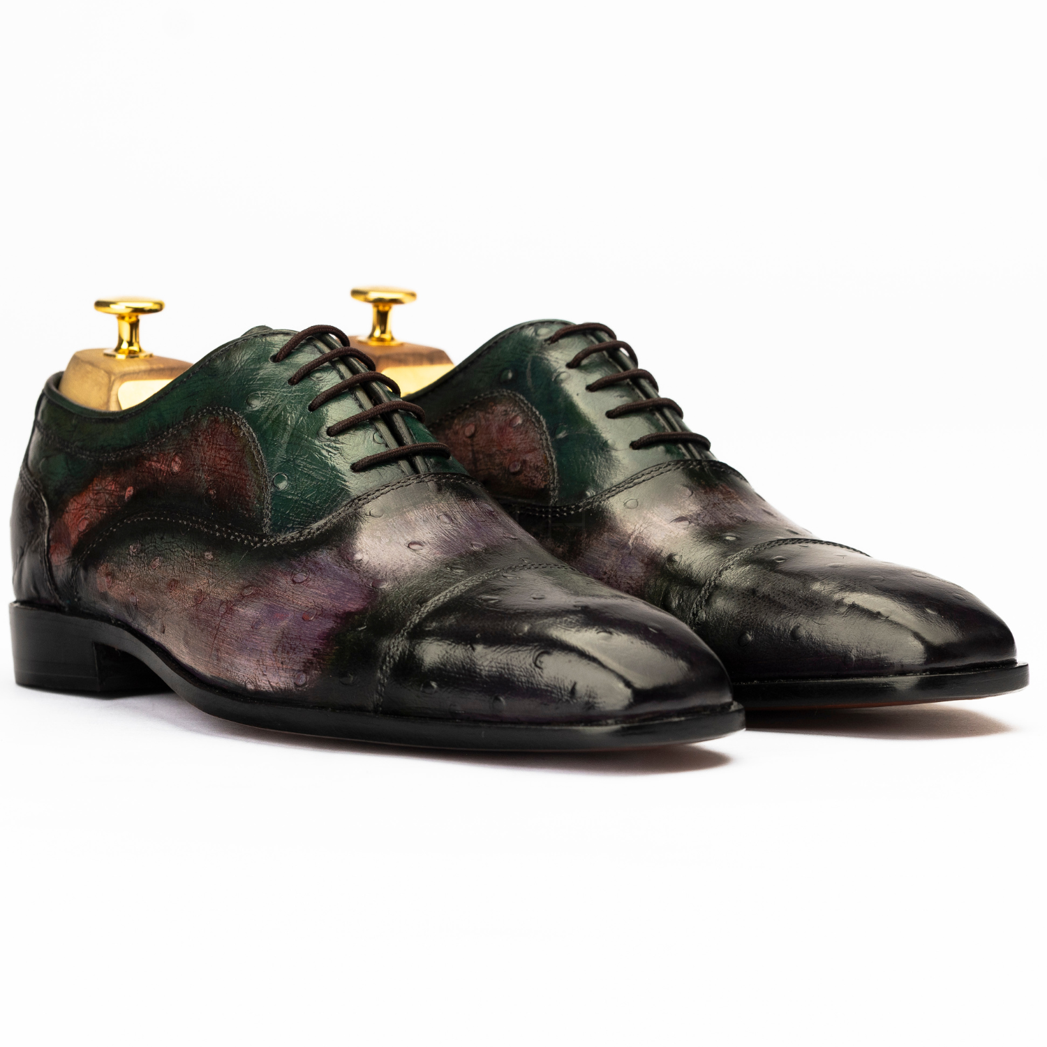 Pair of black and green leather dress shoes on a white background