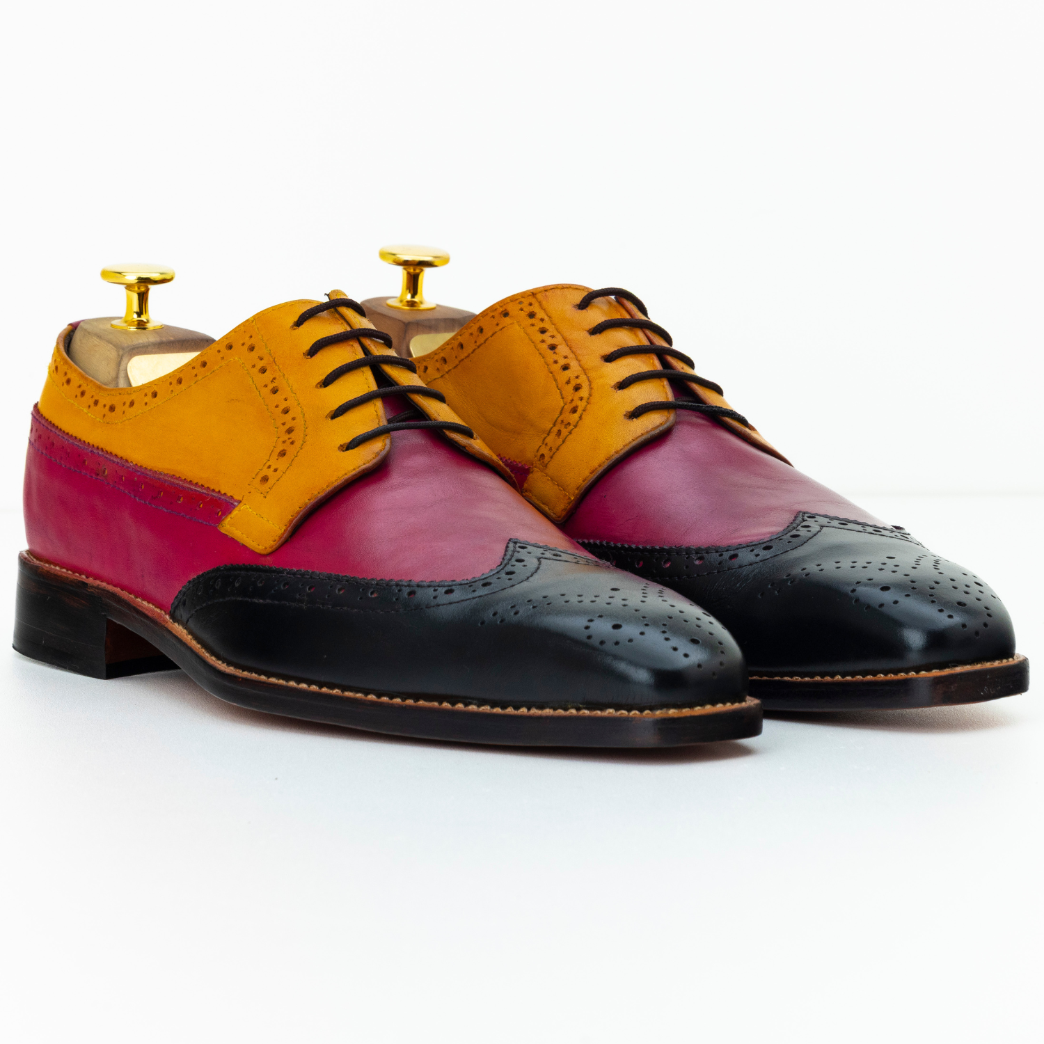 Colorful dress shoes with a mix of red, yellow, and black on a white background