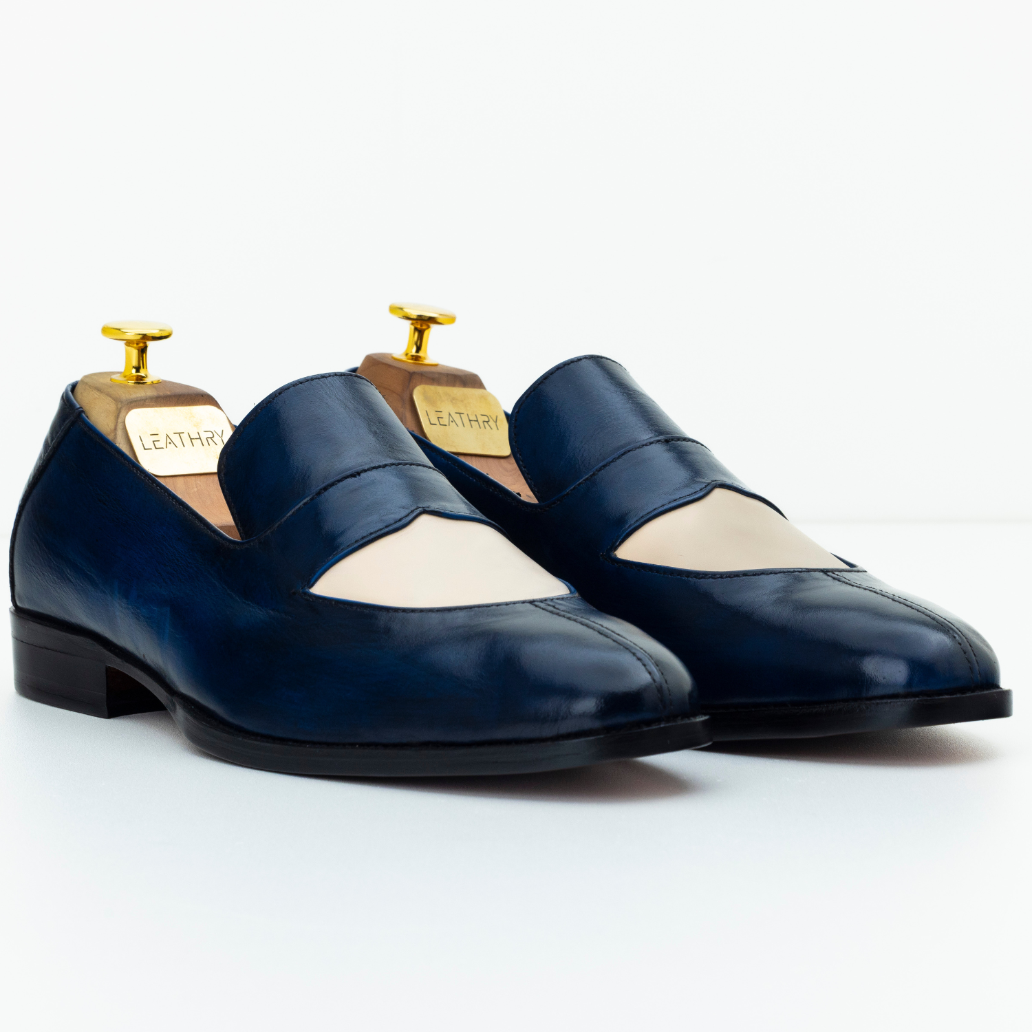 Pair of navy blue loafers with white soles on a white background