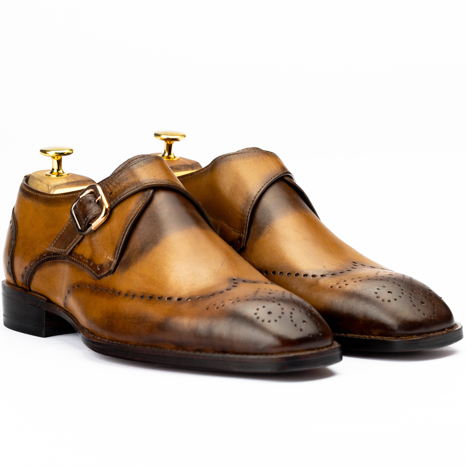 Pair of brown leather shoes with gold buckles on a white background