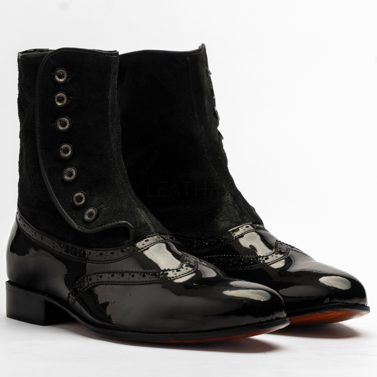 Black boots with patent leather soles on a white background