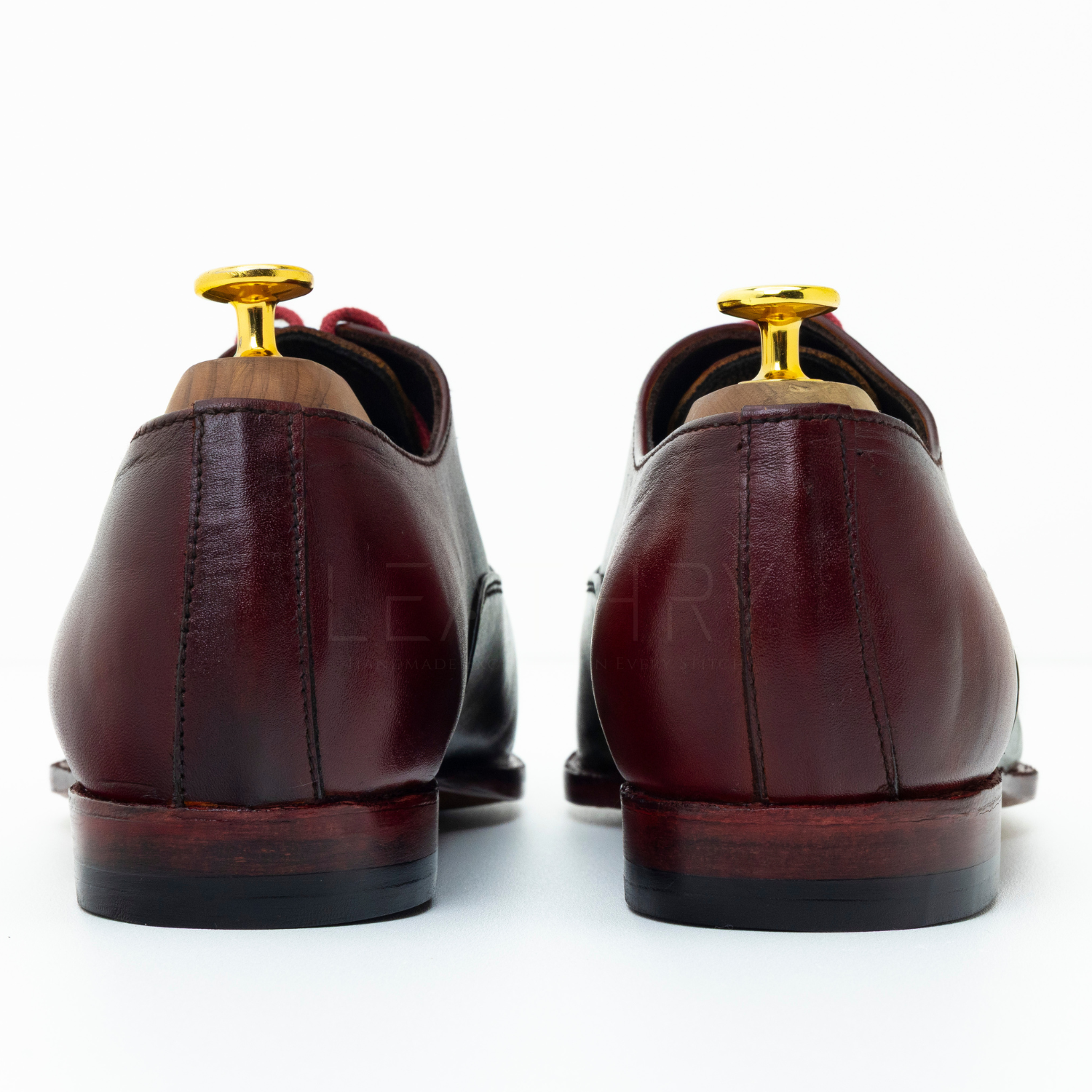 Pair of brown leather shoes with gold buttons on a white background