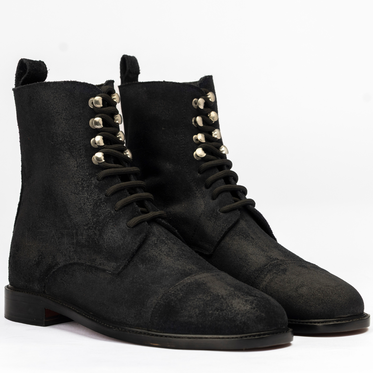 Pair of black suede boots with decorative studs on a white background