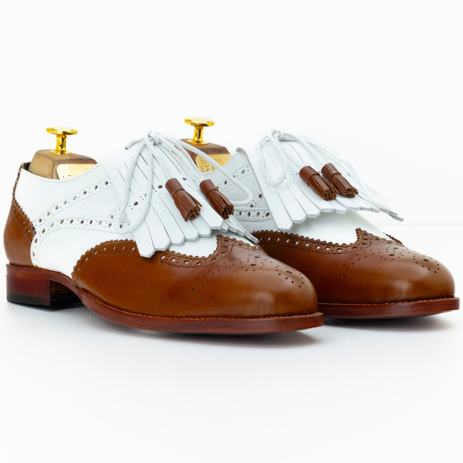 Brown and white shoes with fringes on a white background