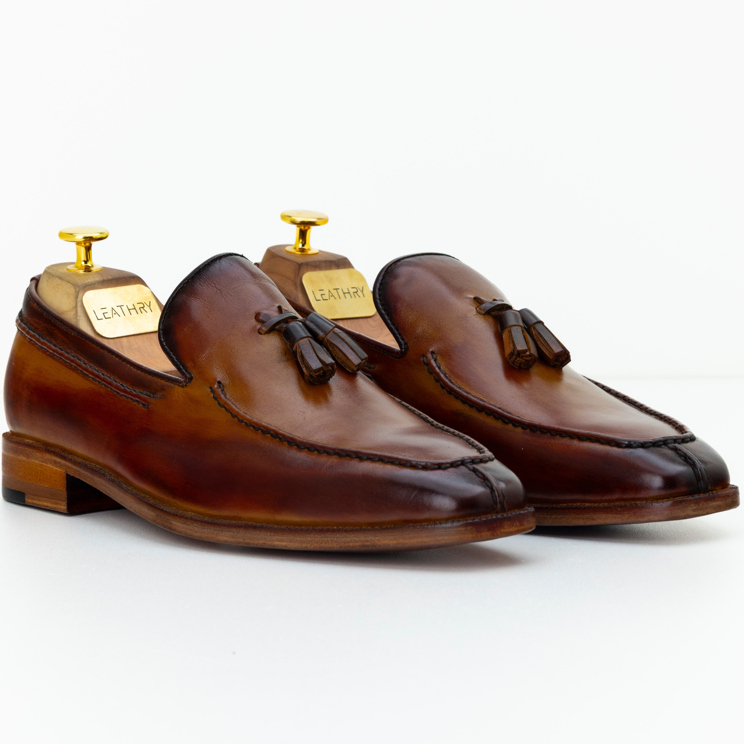 Pair of brown leather loafers with tassels on a white background
