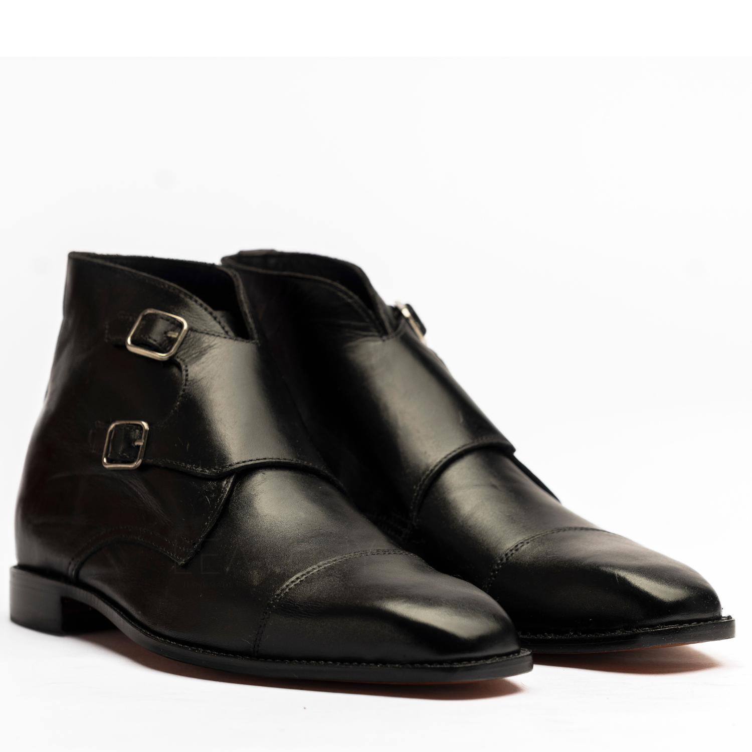 Pair of black leather boots with gold buckles on a white background