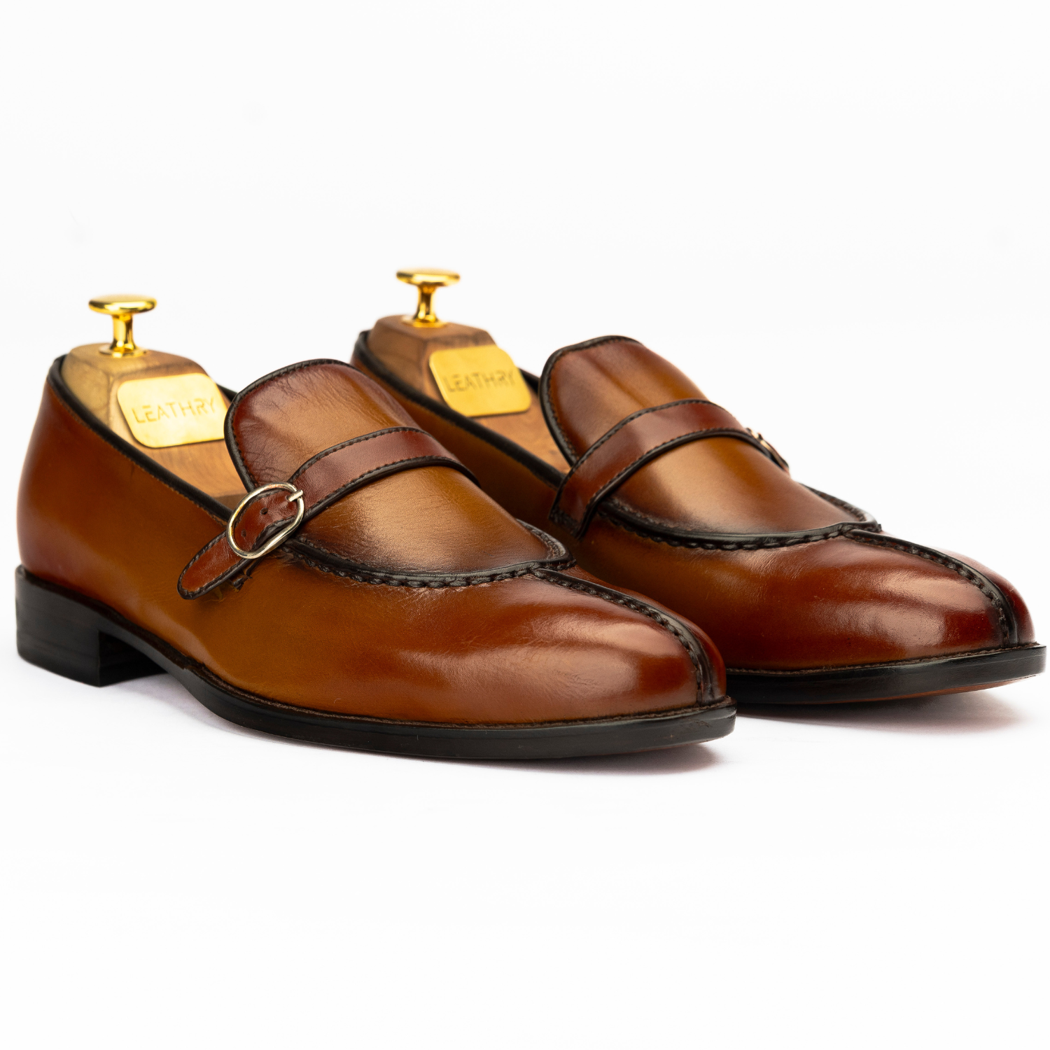 Pair of brown leather shoes with gold buckles on a white background