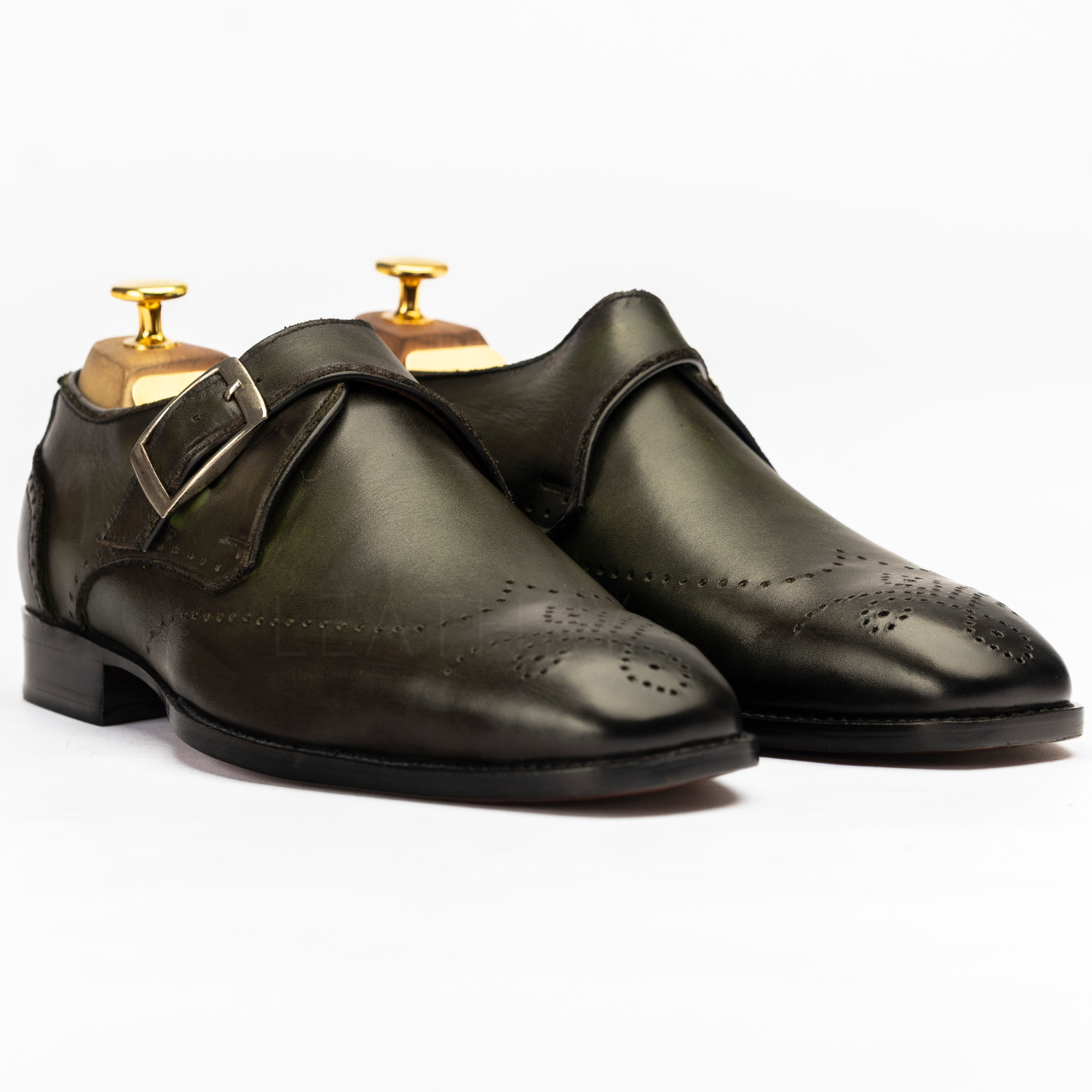 Pair of black leather dress shoes with gold buckles on a white background