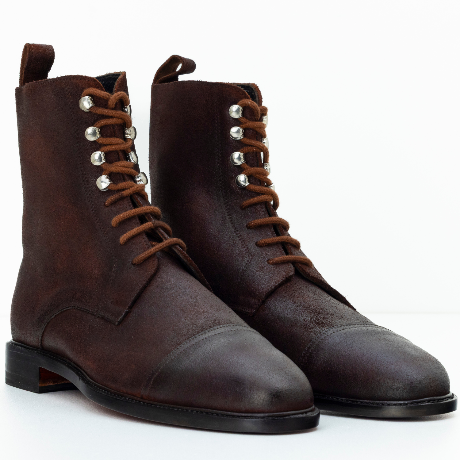 Pair of brown leather boots with laces on a white background