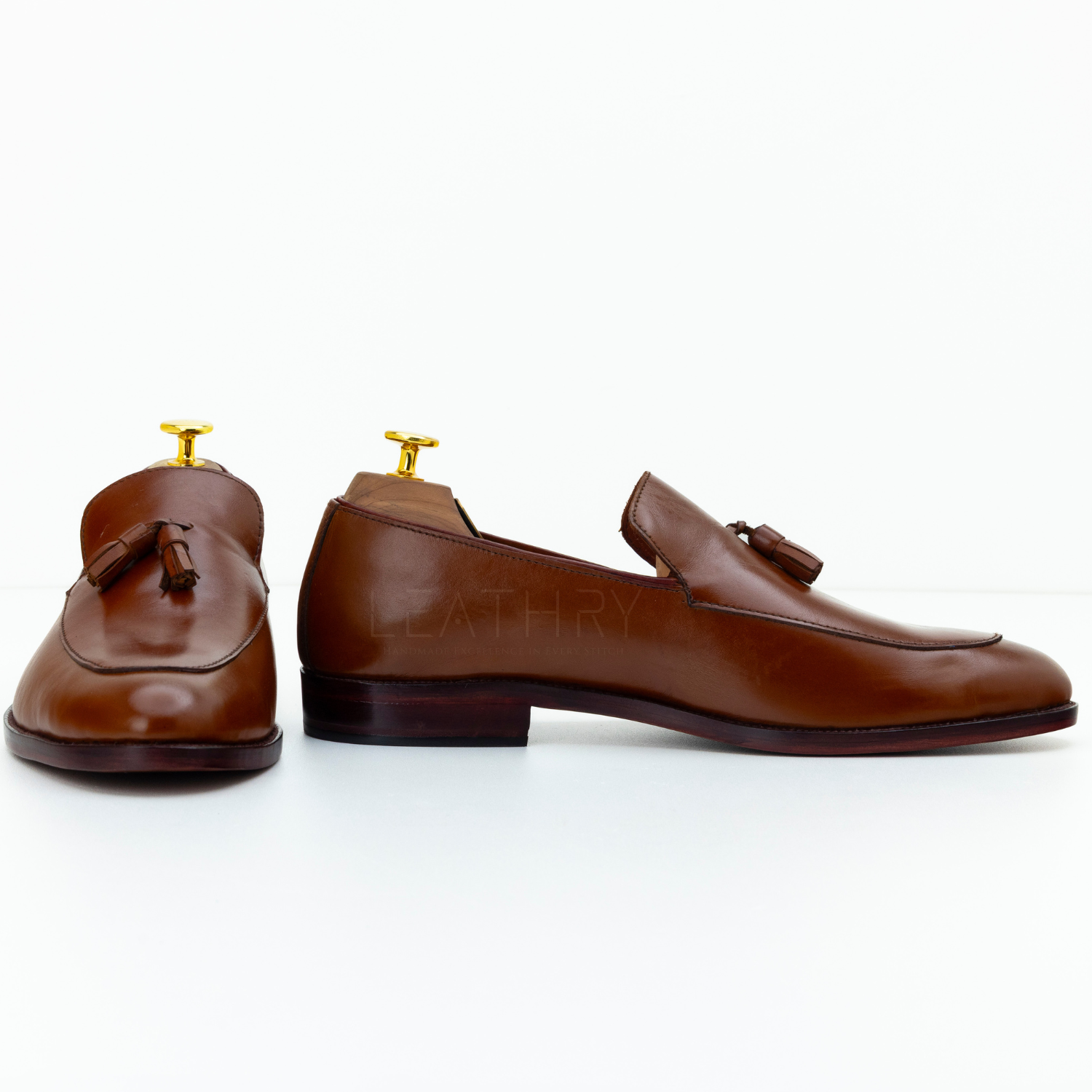 Pair of brown leather loafers with tassels on a white background