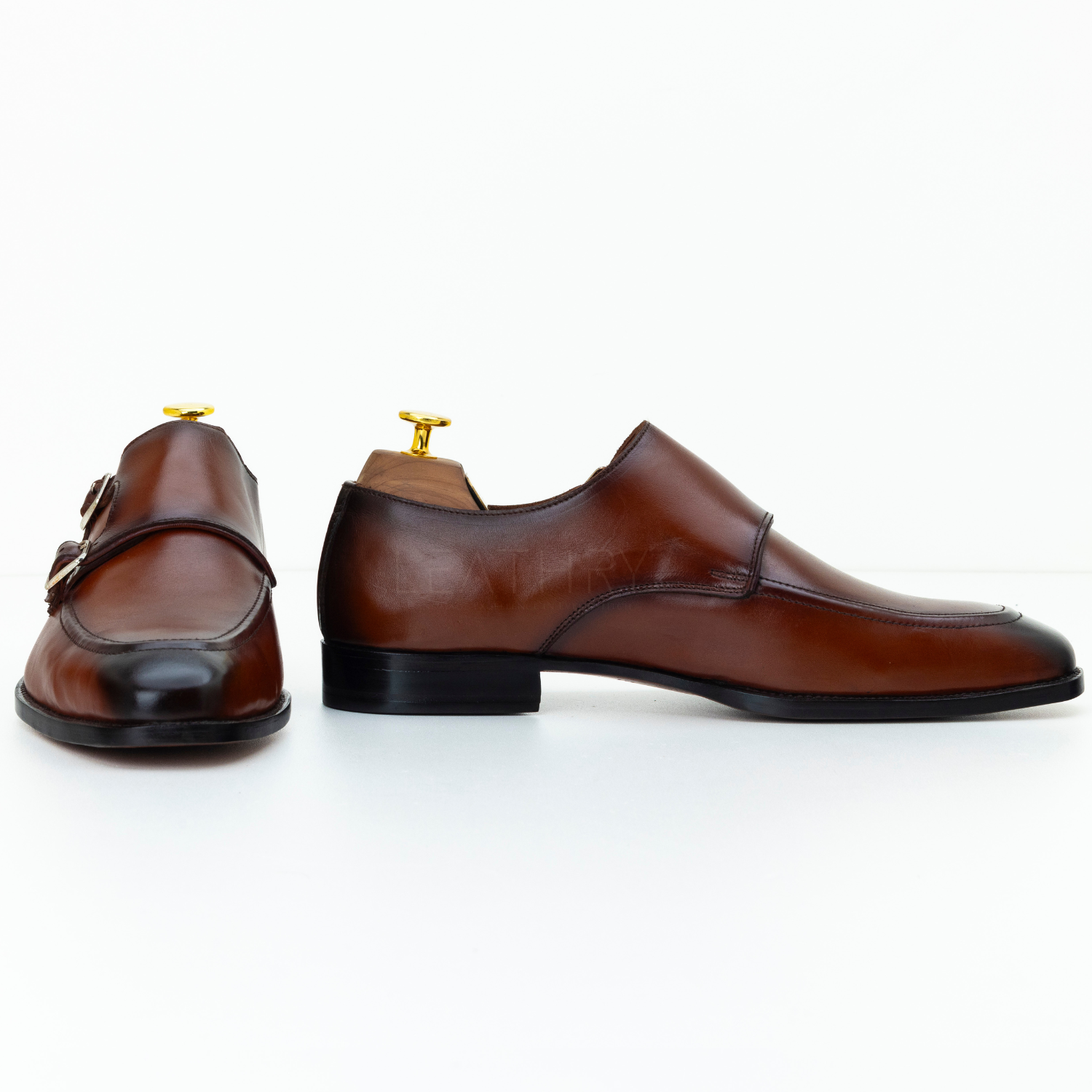 Brown leather shoes with gold buckles on a white background