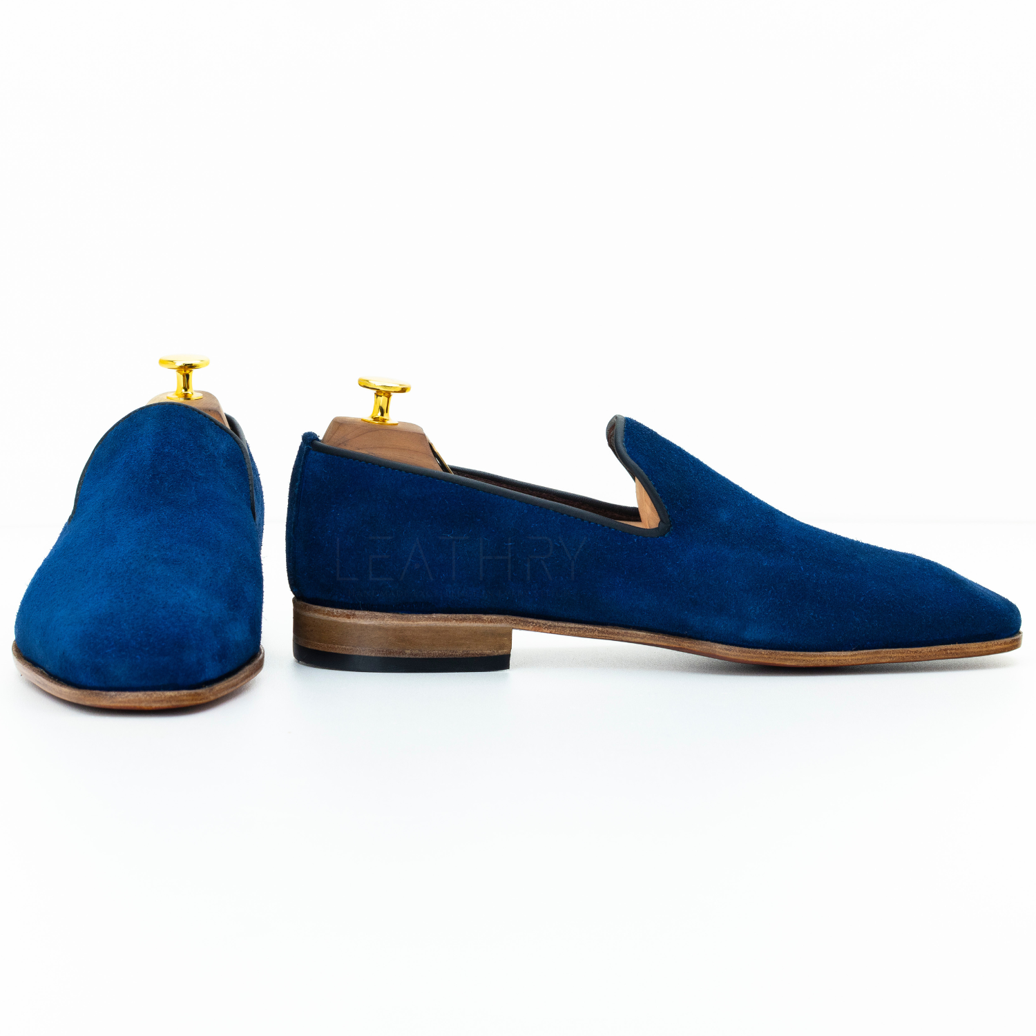 Blue suede loafers on wooden stands with 'Leathry' branding on a white background
