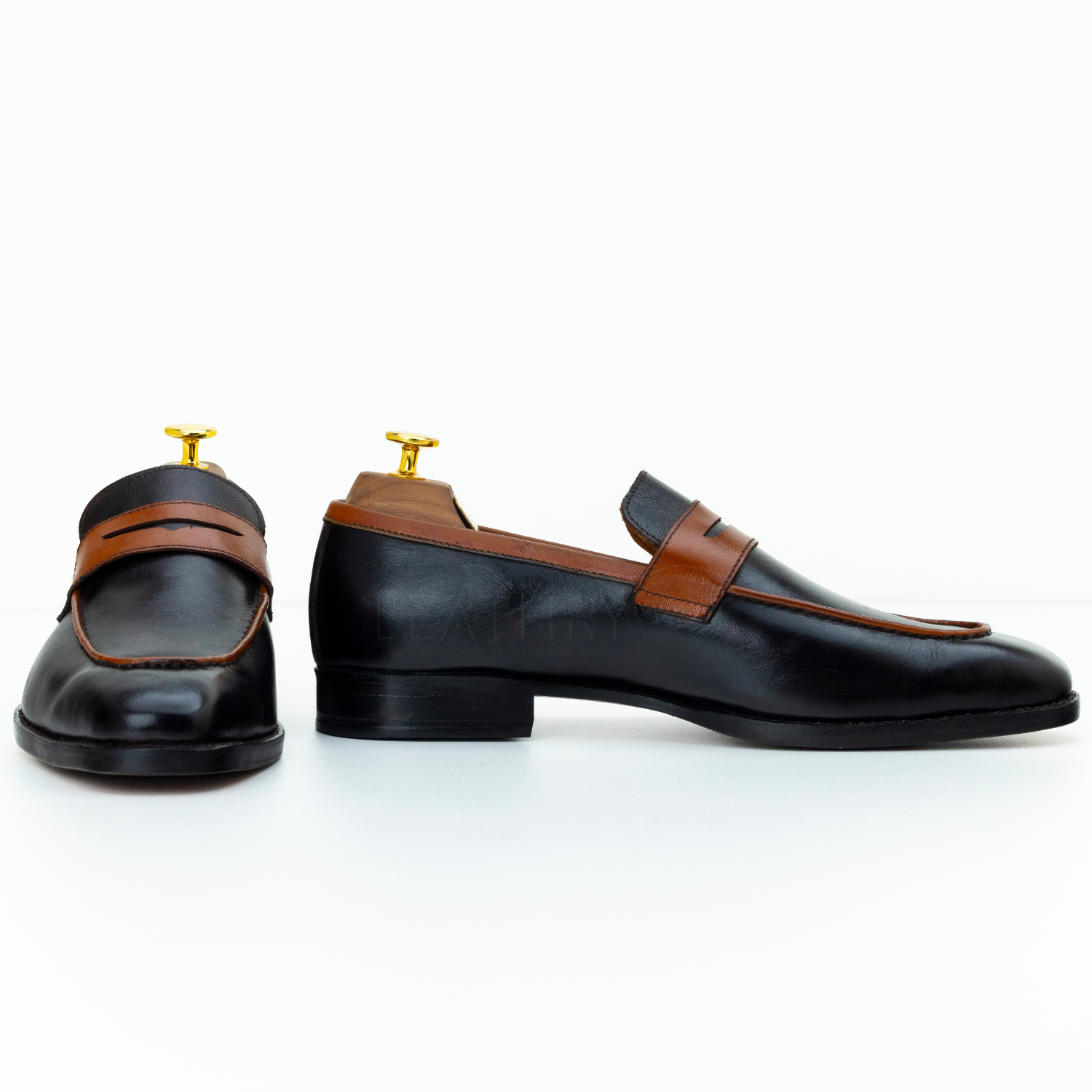 Black leather shoes with brown accents on a white background