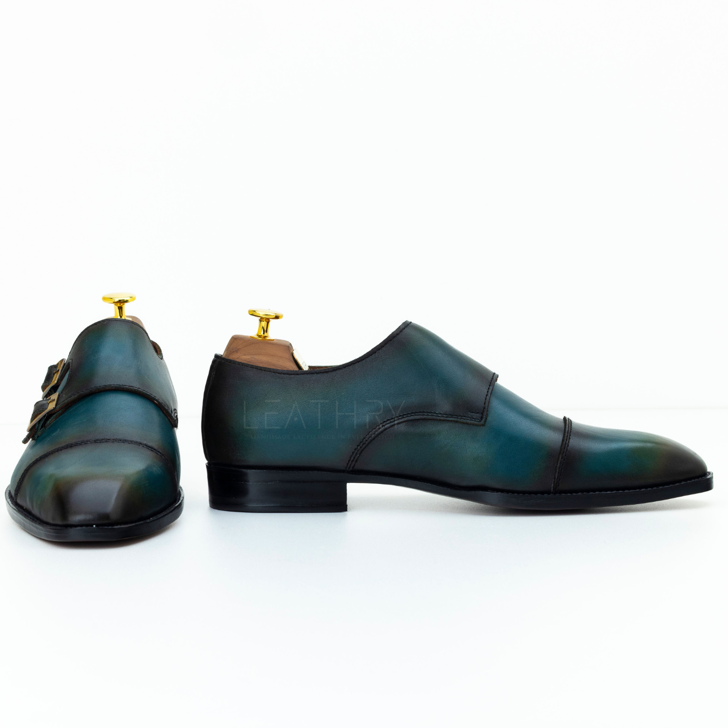 Pair of green leather shoes with gold buckles on a white background