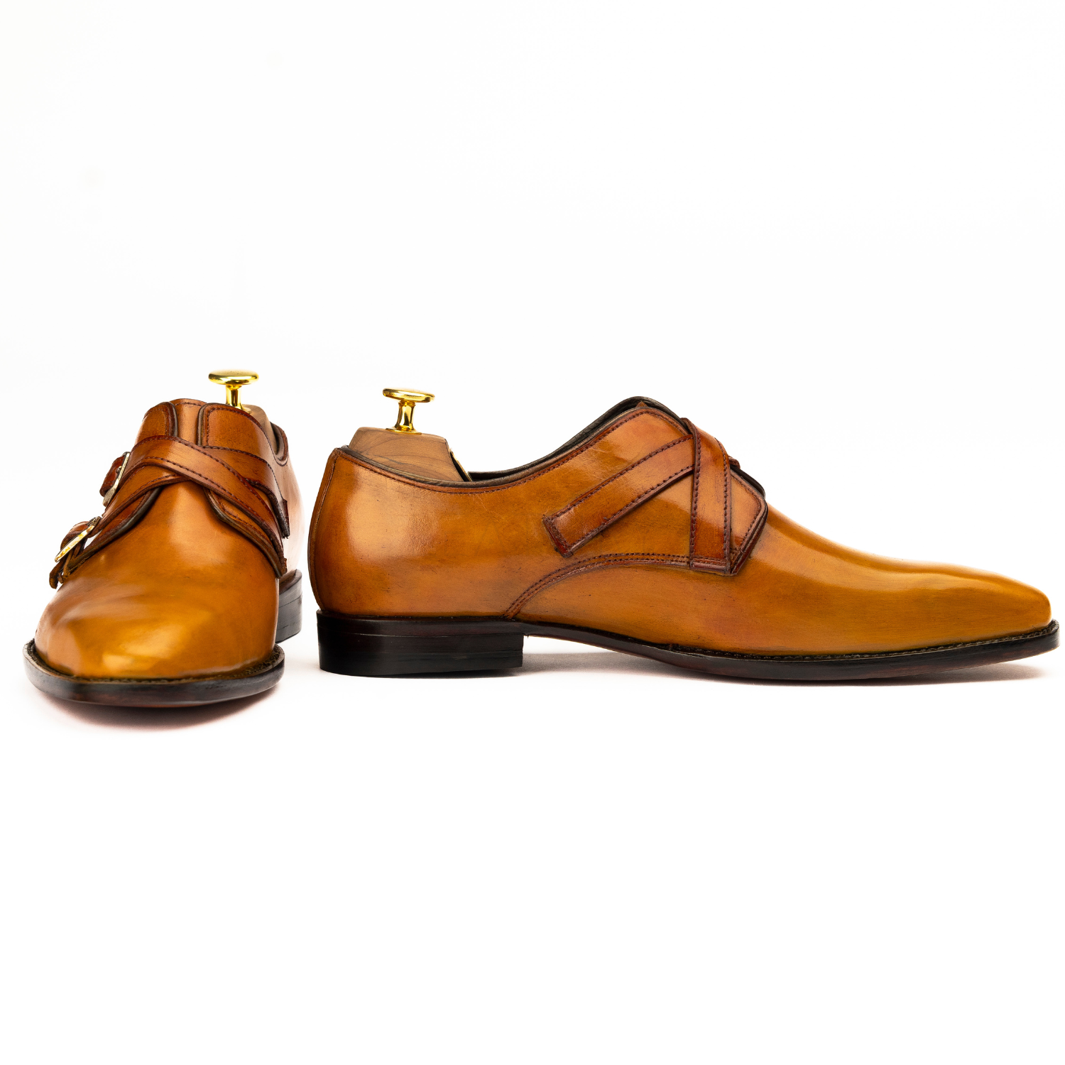 Pair of brown leather shoes with gold buckles on a white background