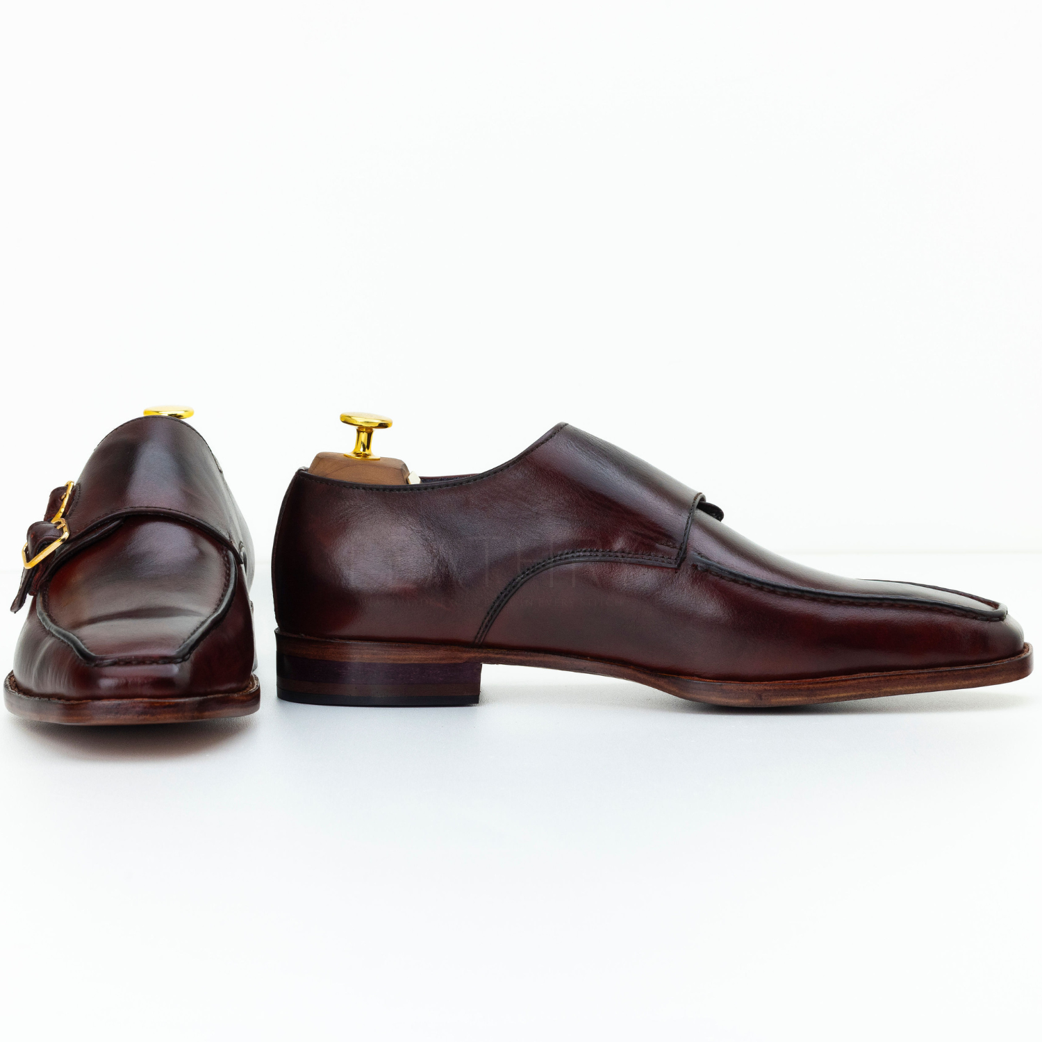 Pair of brown leather shoes with gold buckles on a white background