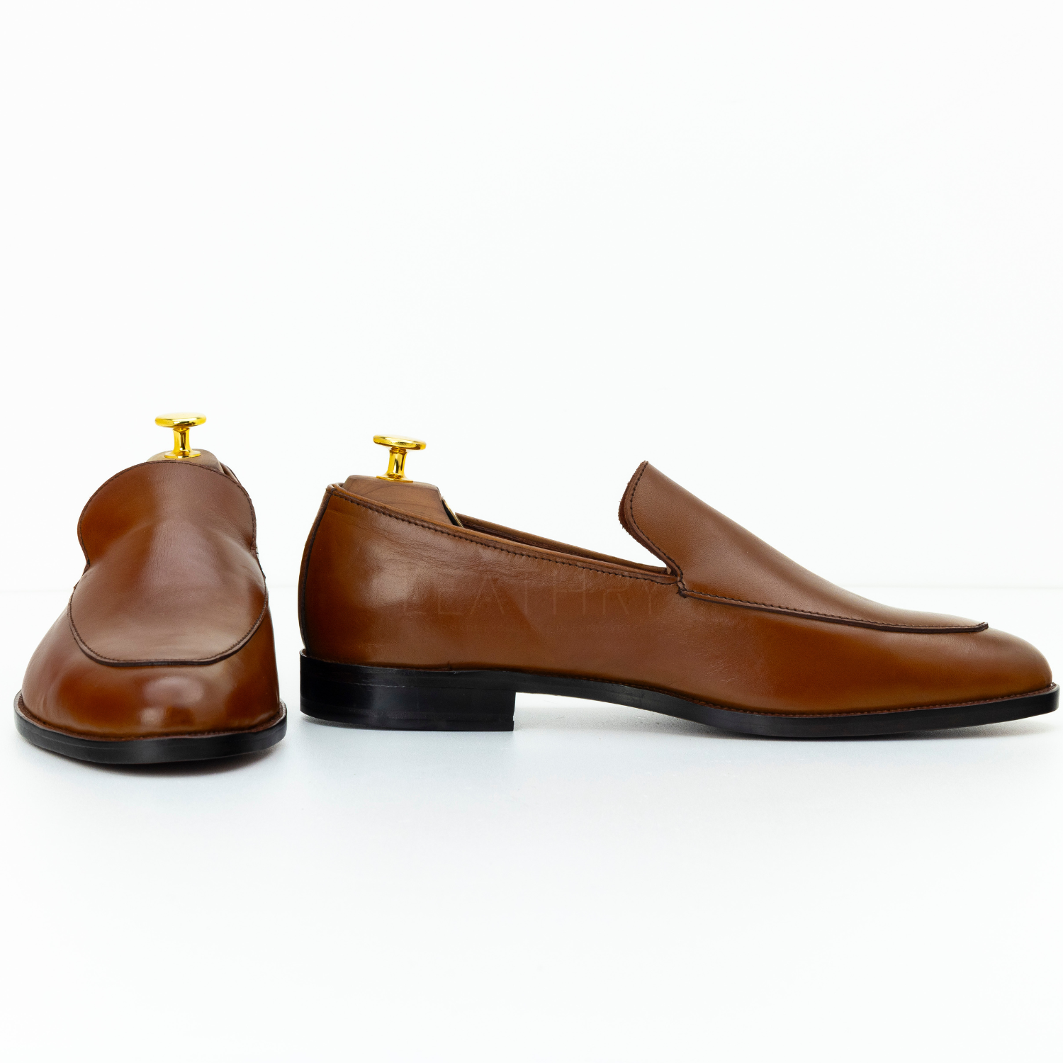 Pair of brown leather loafers on a white background