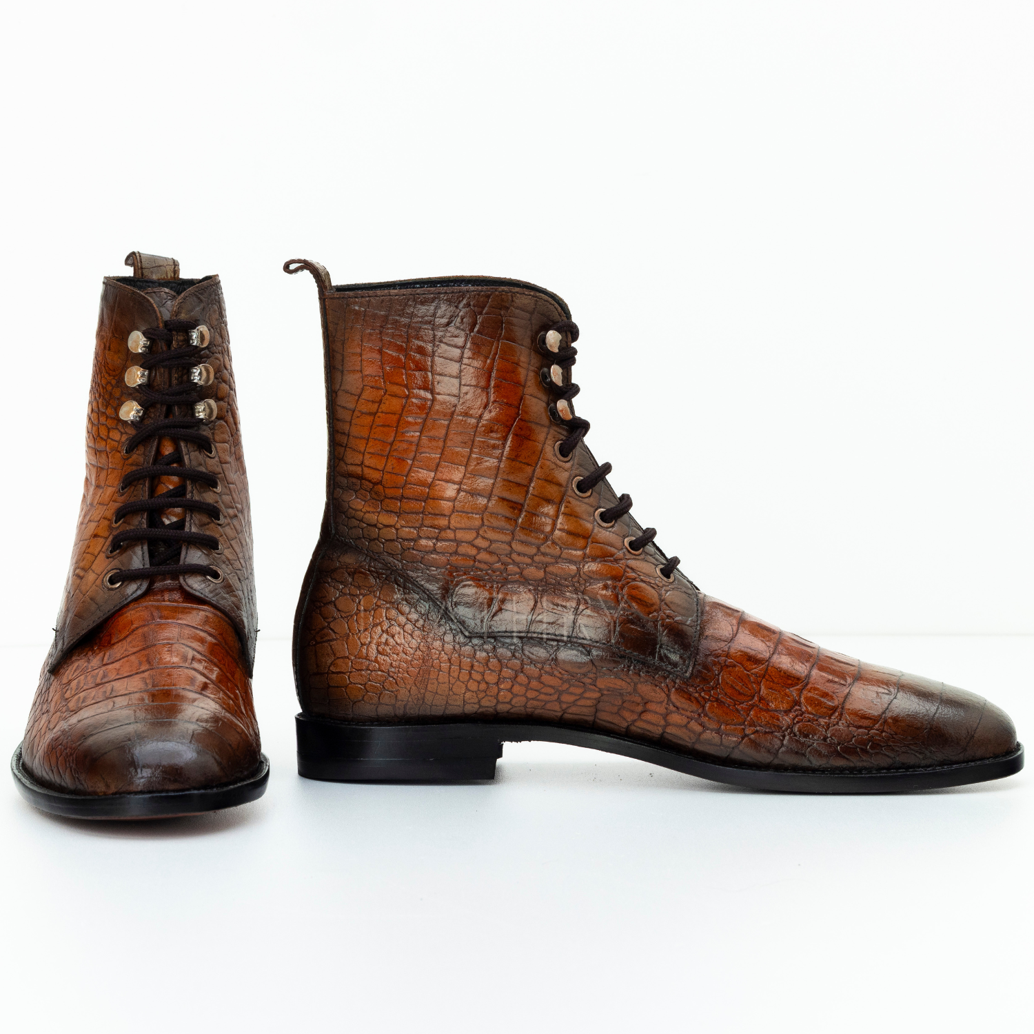 Brown leather boots with crocodile texture on a white background