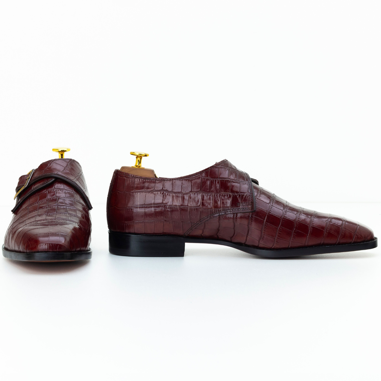 Pair of brown dress shoes with gold buckles on a white background