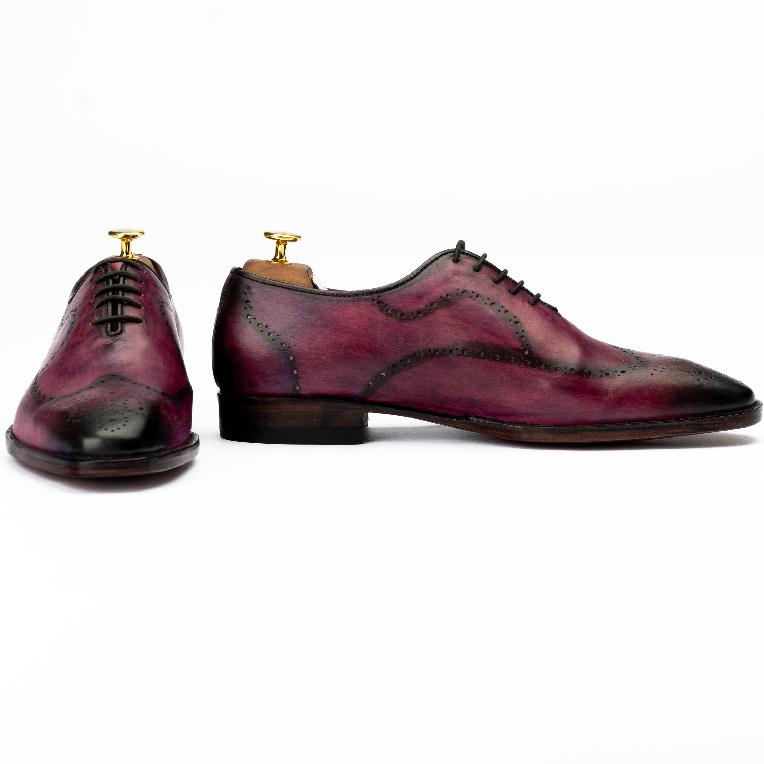 Pair of maroon leather shoes with gold accents on a white background