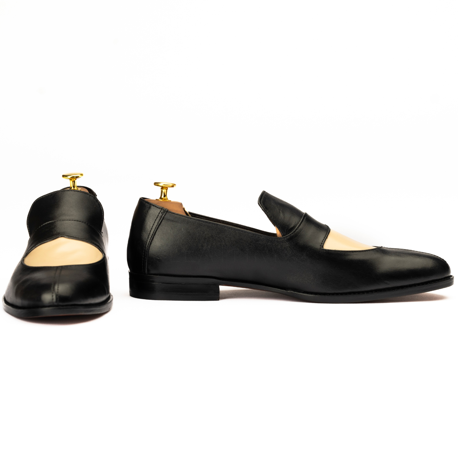 Pair of black loafers with gold accents on a white background