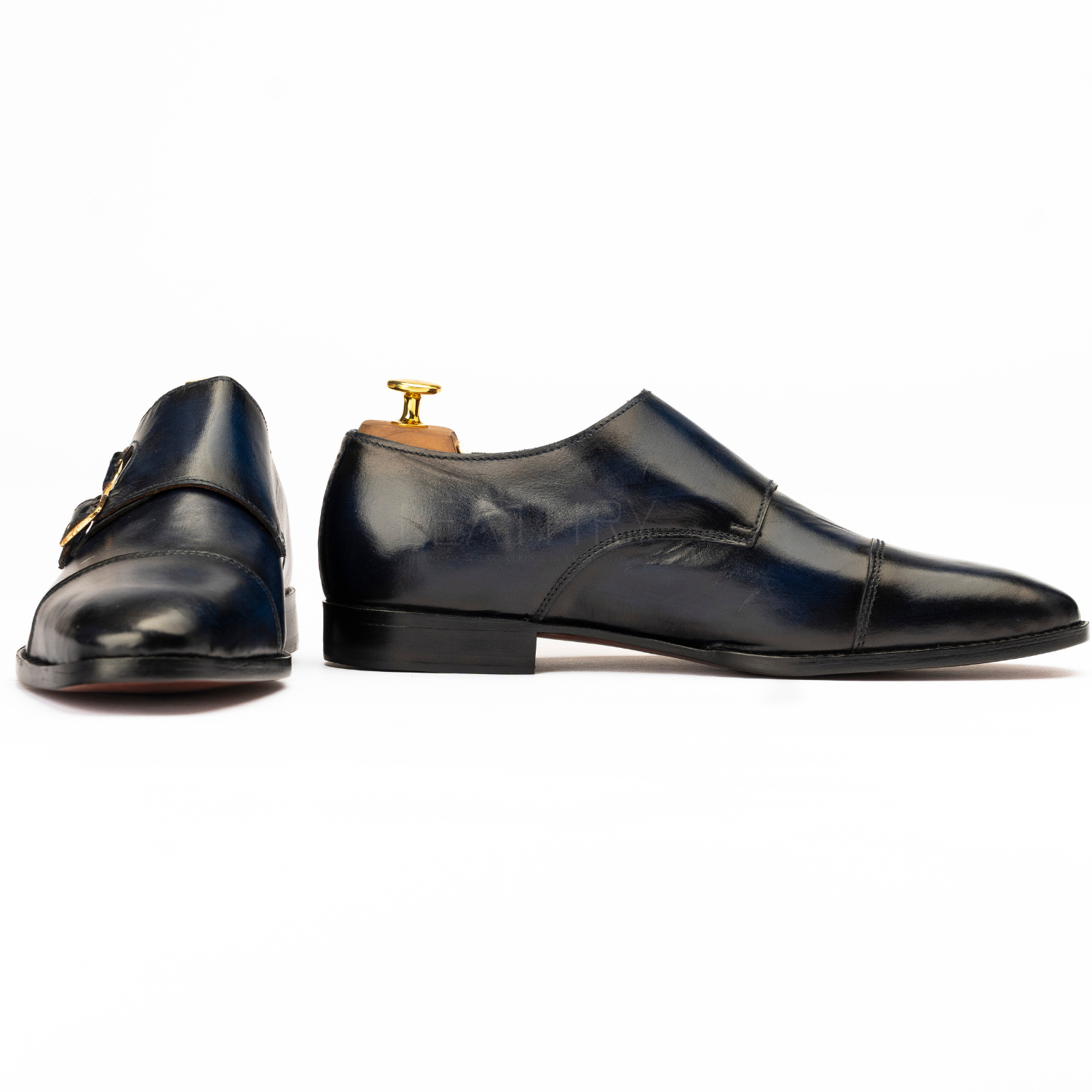 Pair of black dress shoes with a gold buckle on a white background