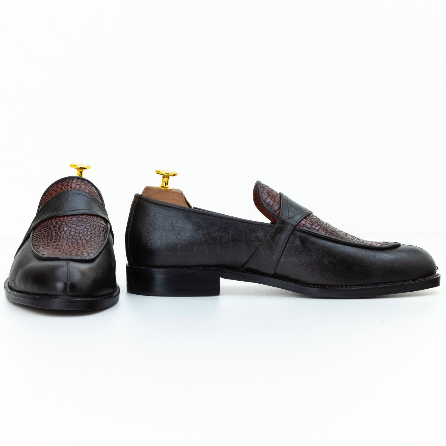 Pair of black leather loafers with brown accents on a white background