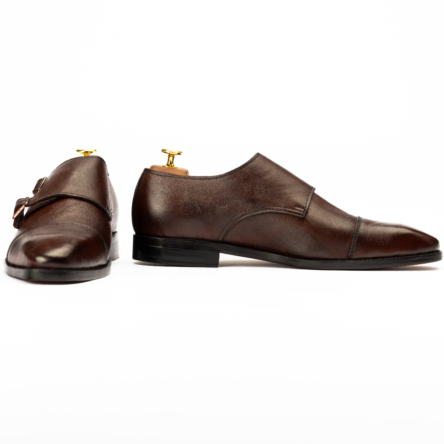 Pair of brown leather shoes with gold buckles on a white background
