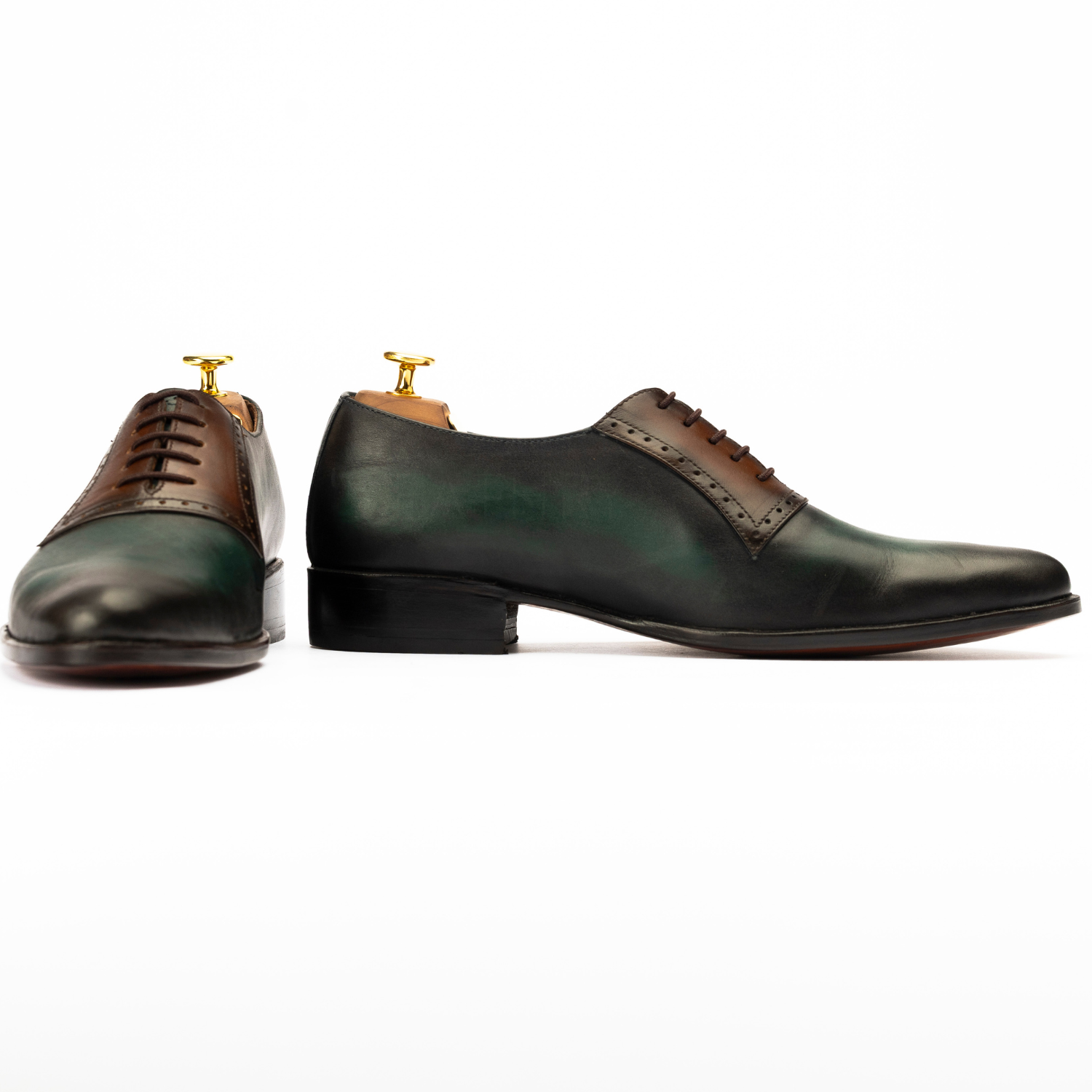 Pair of green and brown leather dress shoes on a white background
