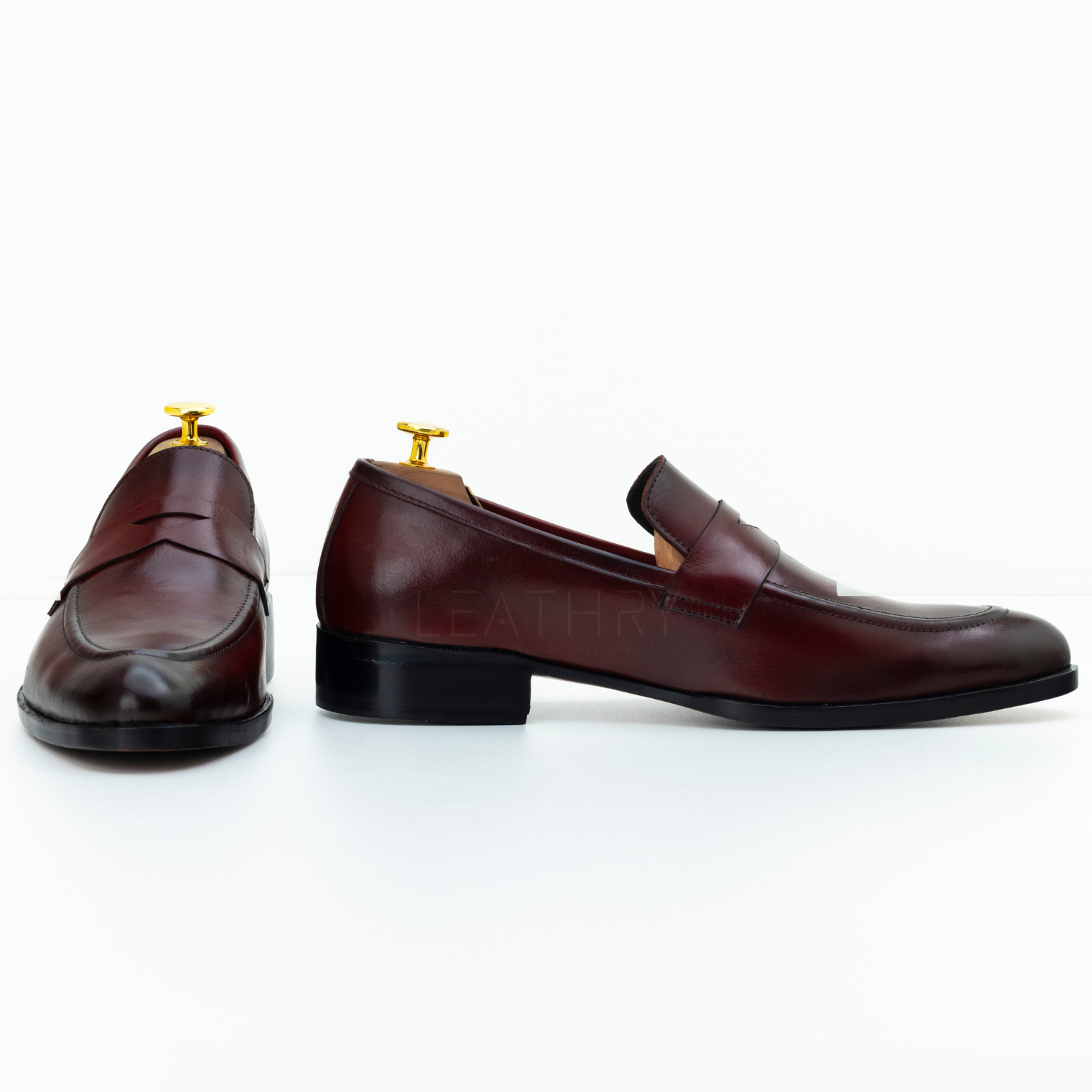 Pair of brown leather loafers with gold buckles on a white background