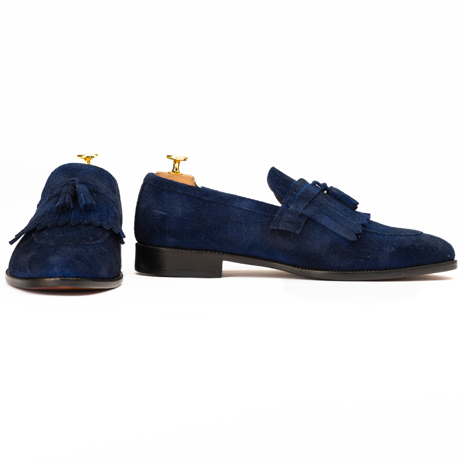 Pair of blue suede loafers with tassels on a white background