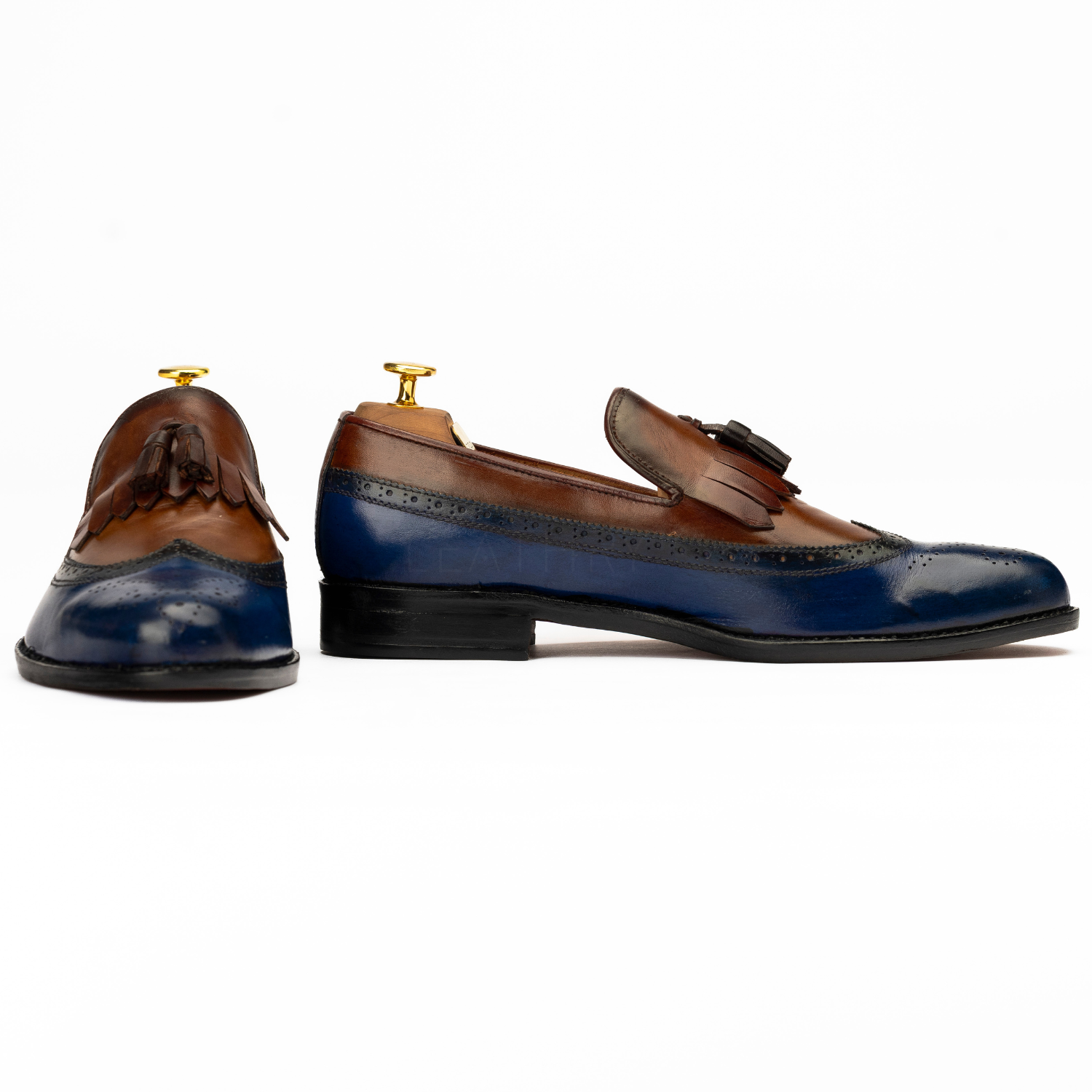 Pair of brown and blue leather loafers on a white background