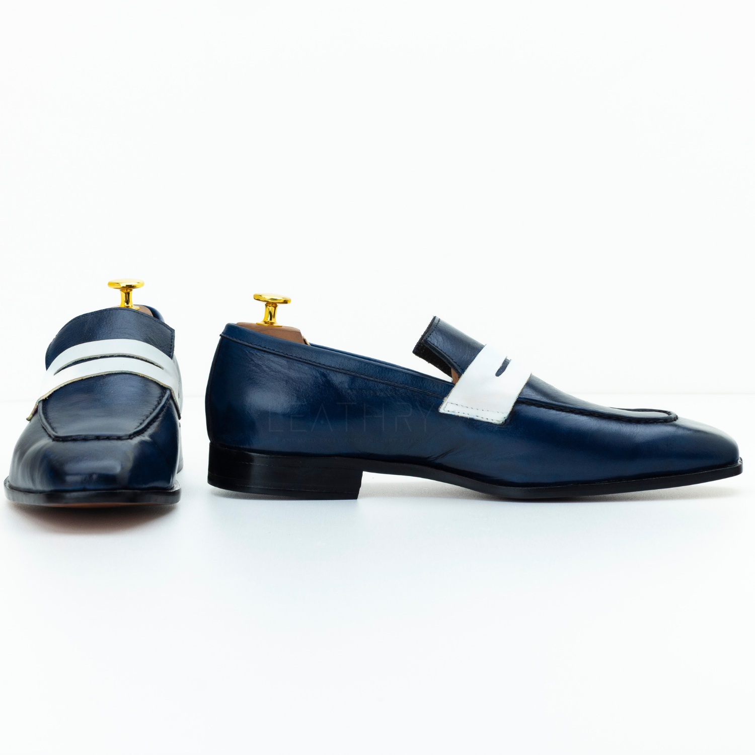 Pair of navy loafers with white straps on a white background