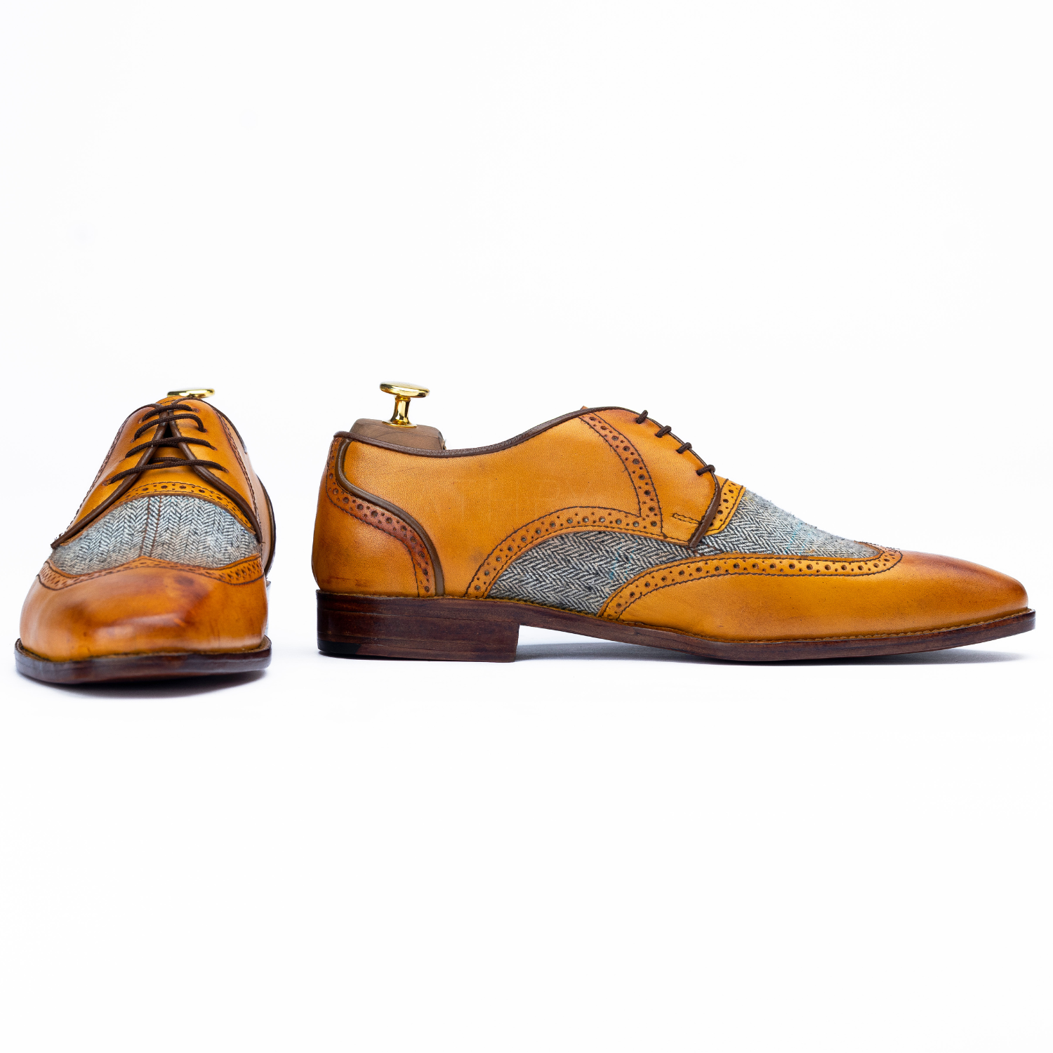 Pair of tan leather shoes with gray fabric accents on a white background