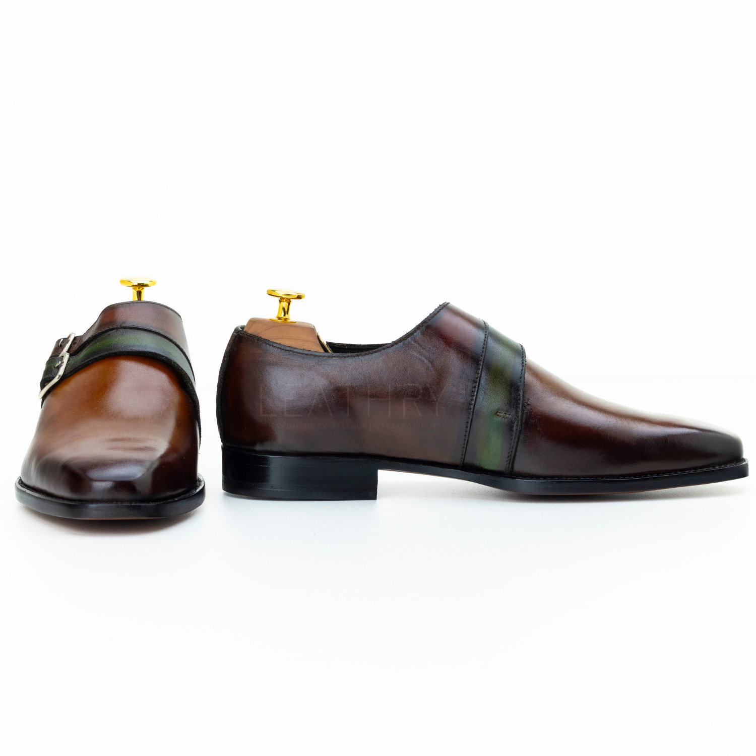 Pair of brown leather shoes with gold buckles on a white background