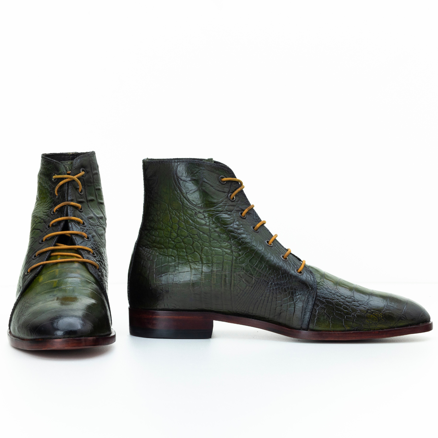 Green leather boots with brown soles on a white background