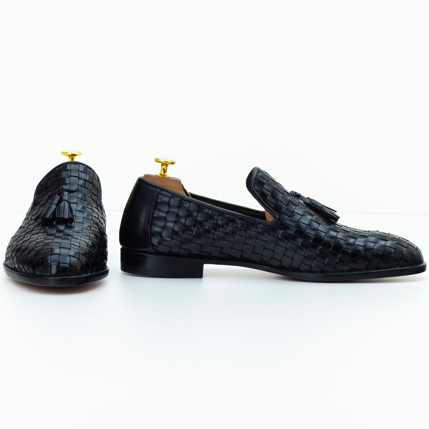 Black textured loafers with tassels on a white background