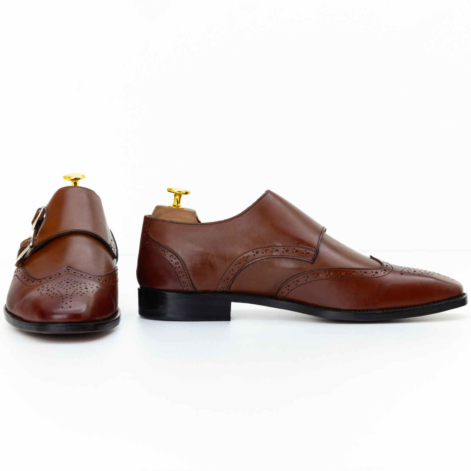 Pair of brown leather shoes with gold buckles on a white background