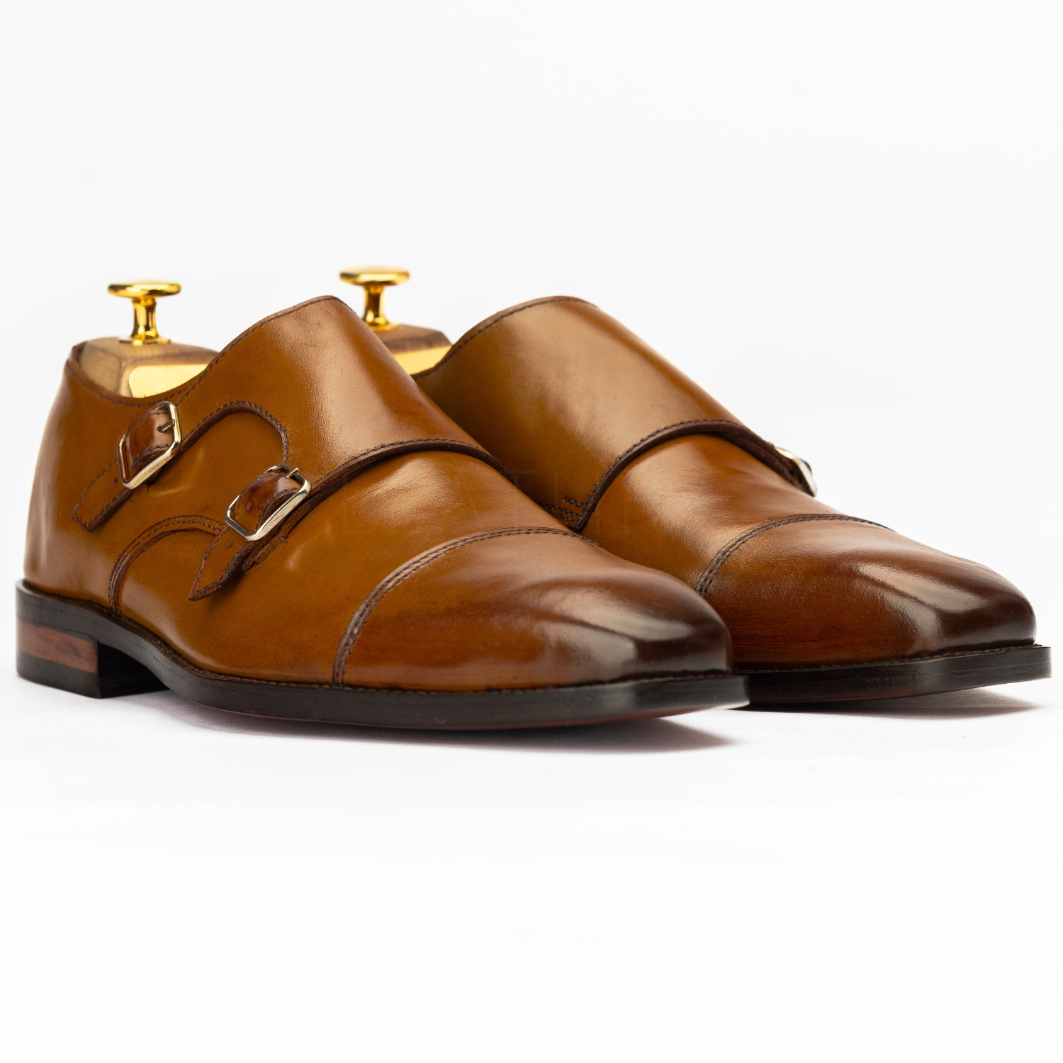 Pair of brown leather shoes with gold buckles on a white background