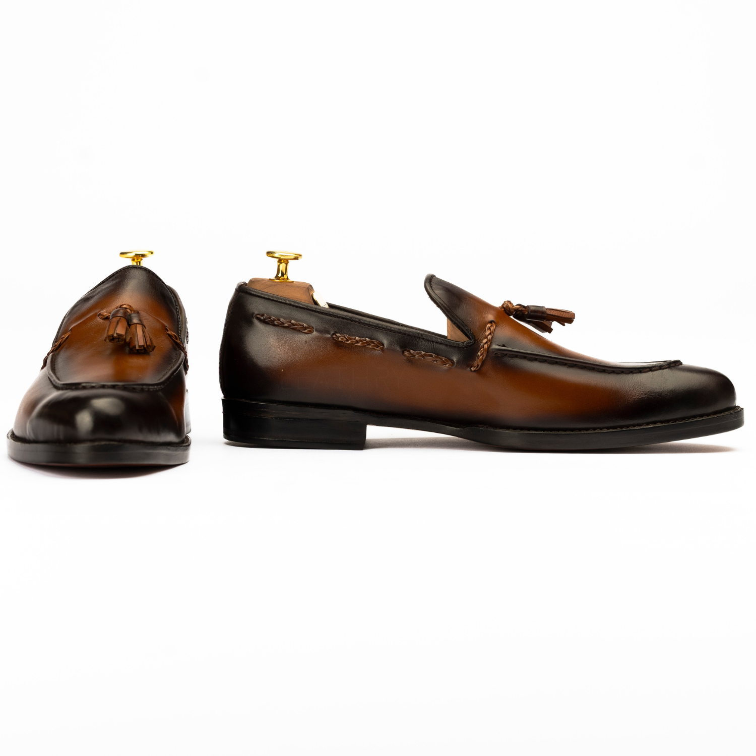 Pair of brown leather loafers with tassels on a white background