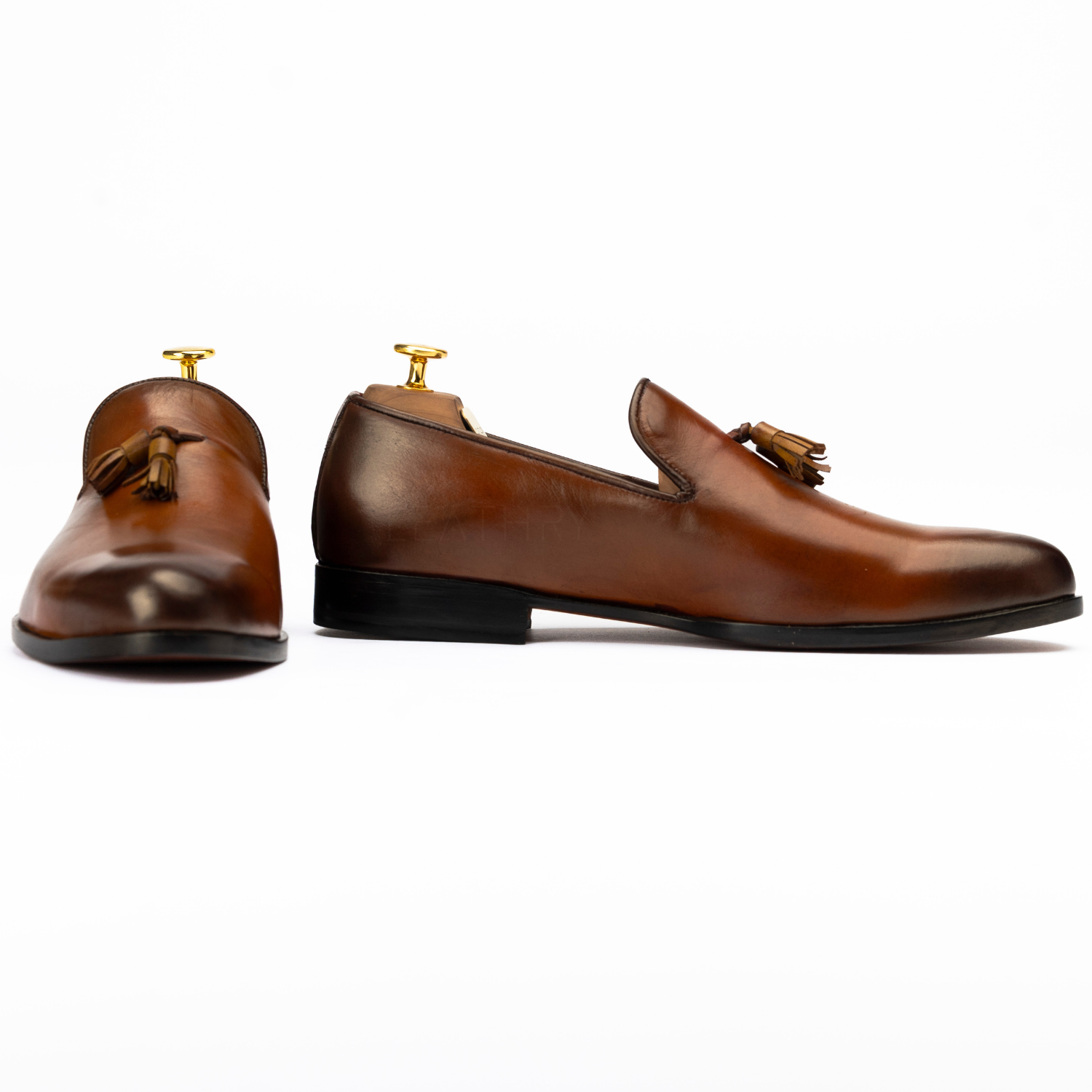 Pair of brown leather loafers with tassels on a white background