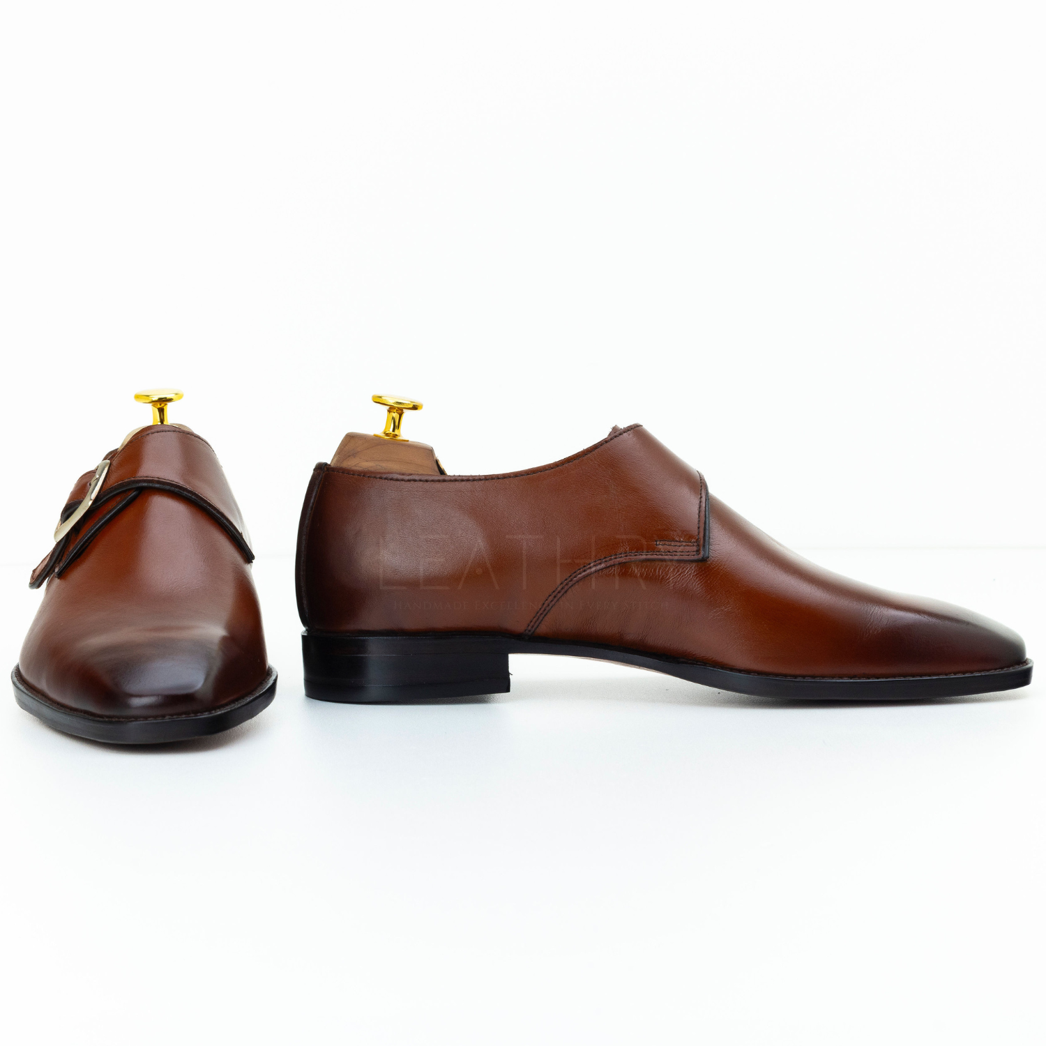 Pair of brown leather shoes with gold buckles on a white background