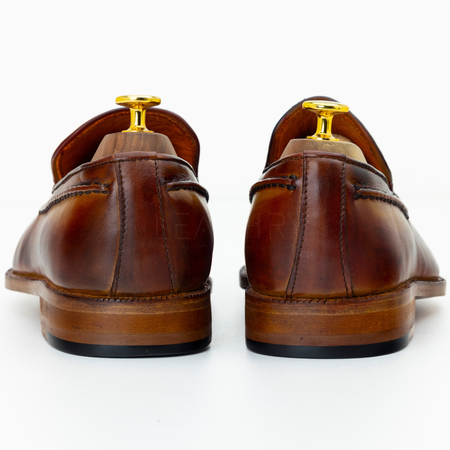 Brown leather shoes with gold accents on a white background