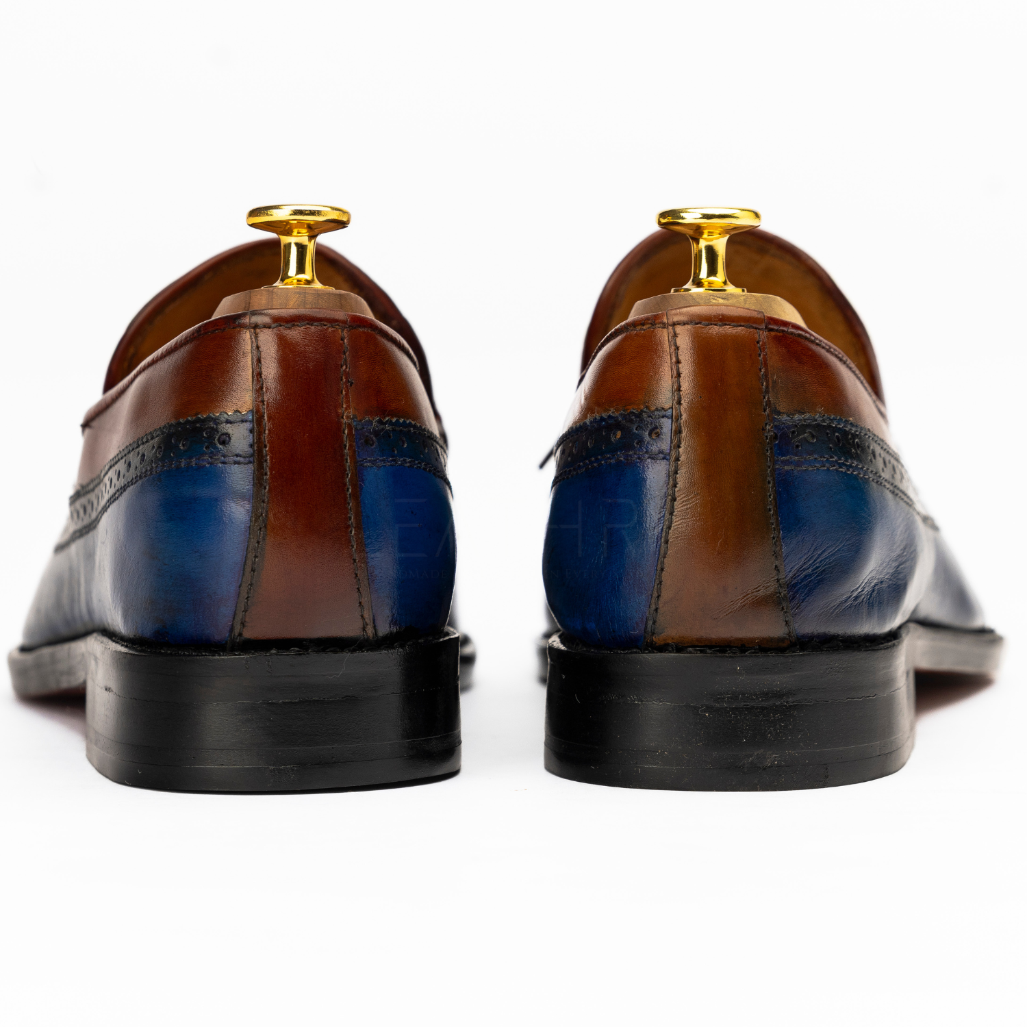 Pair of brown and blue leather shoes with gold accents on a white background