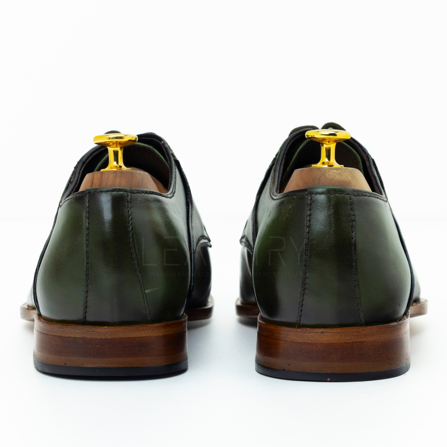 Green leather shoes with brown soles on a white background