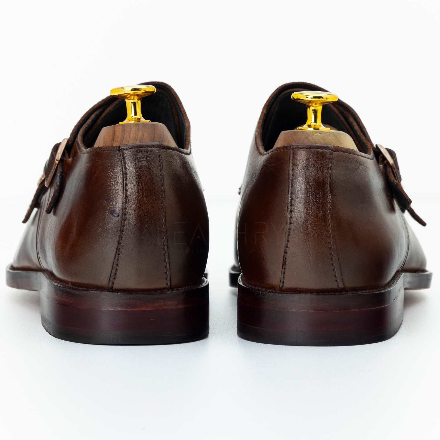 Brown leather shoes with gold accents on a white background