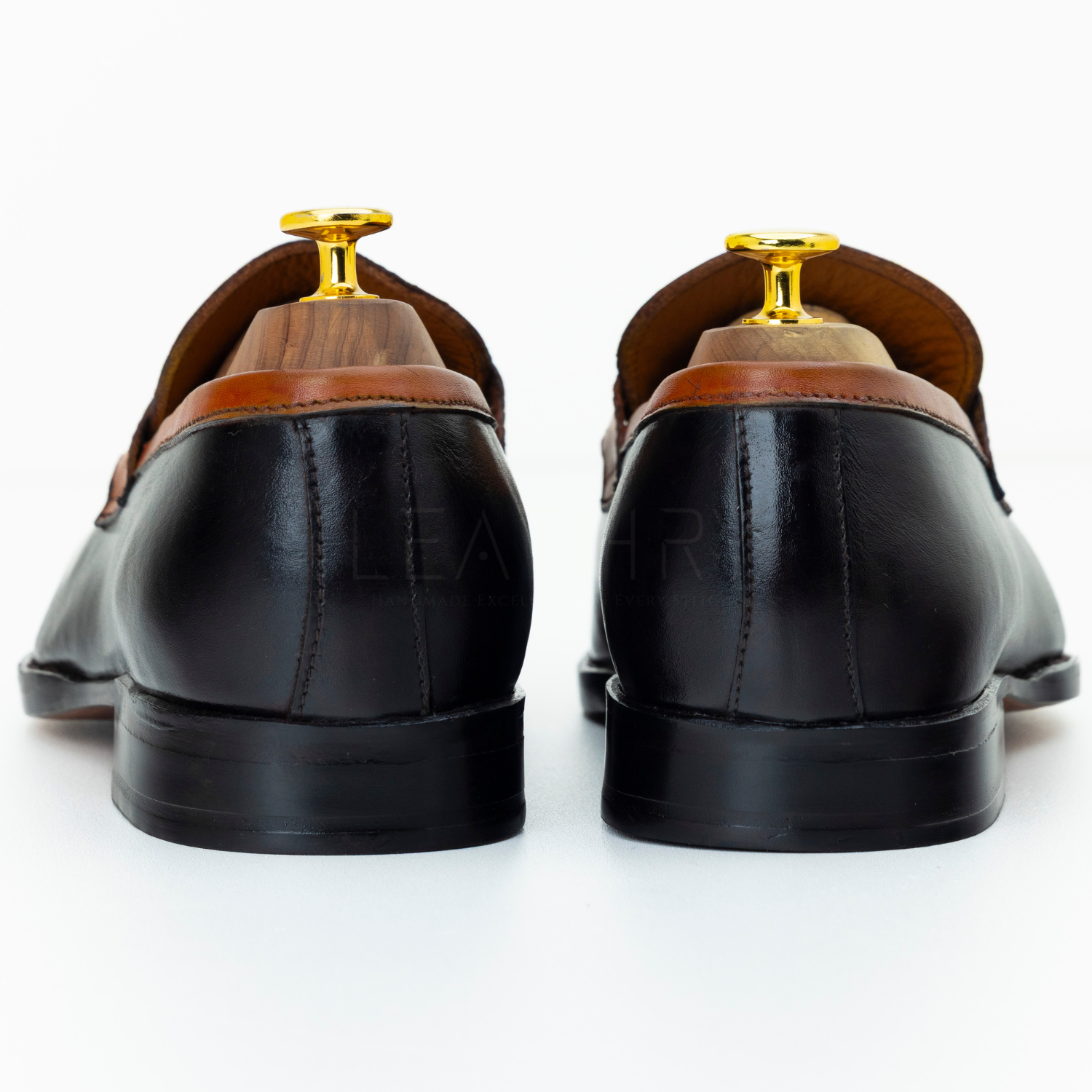 Pair of black dress shoes with brown soles on a white background