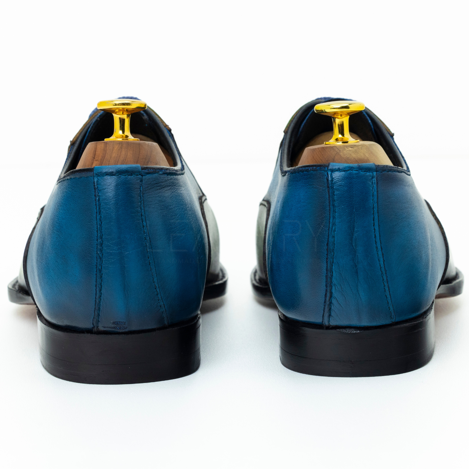 Blue leather shoes with gold accents on a white background